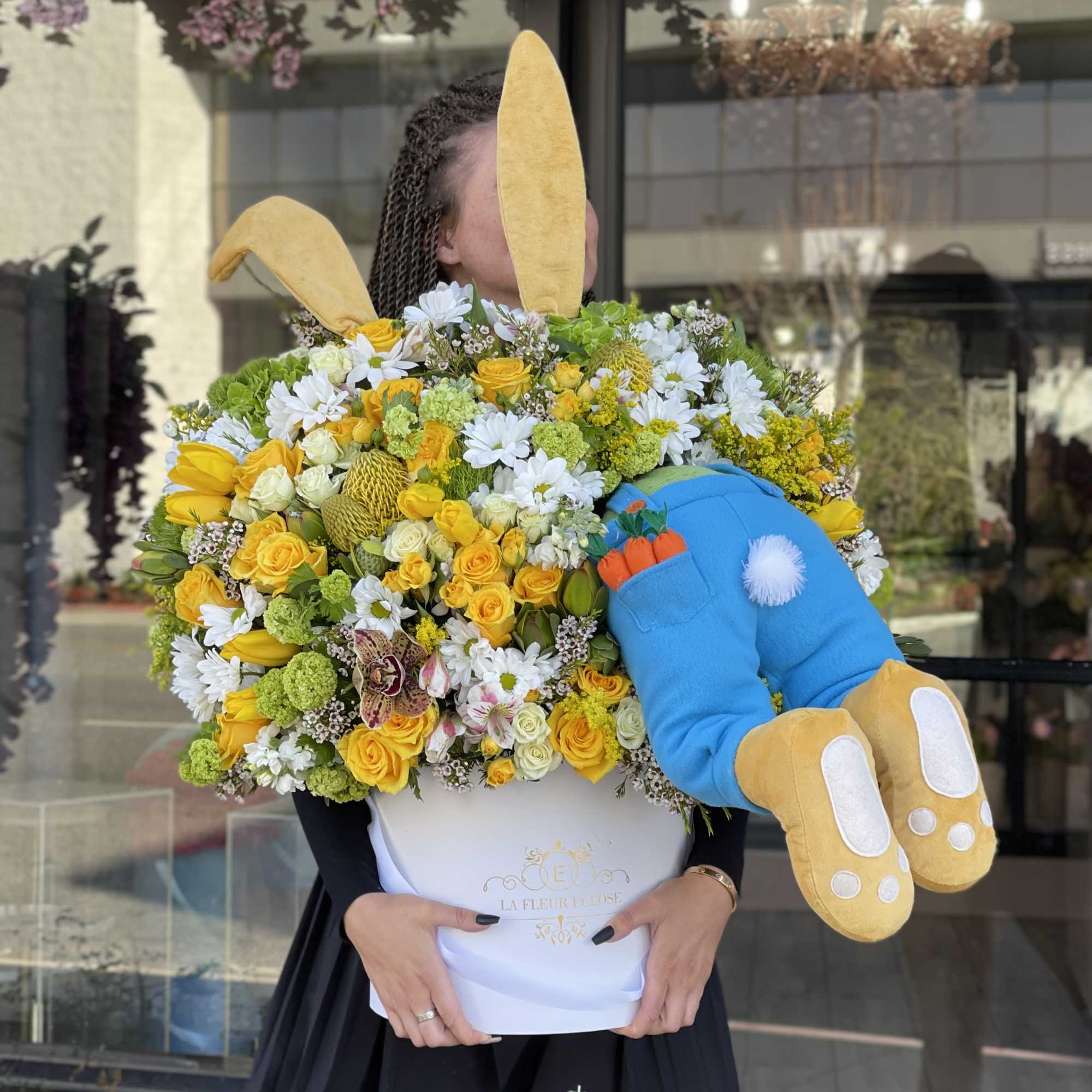 Large yellow and white flower arrangement with a plush bunny in a white box