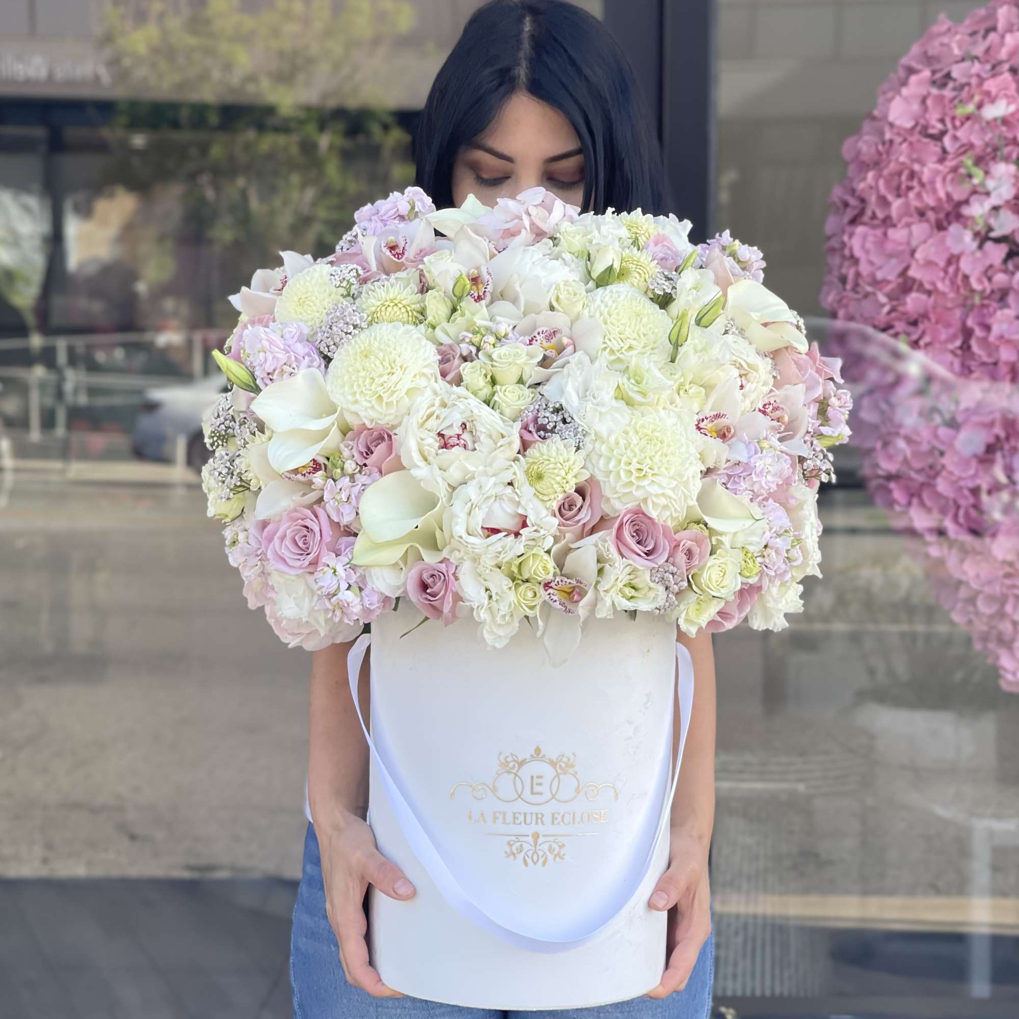Large pastel bouquet in a white hatbox held by a woman