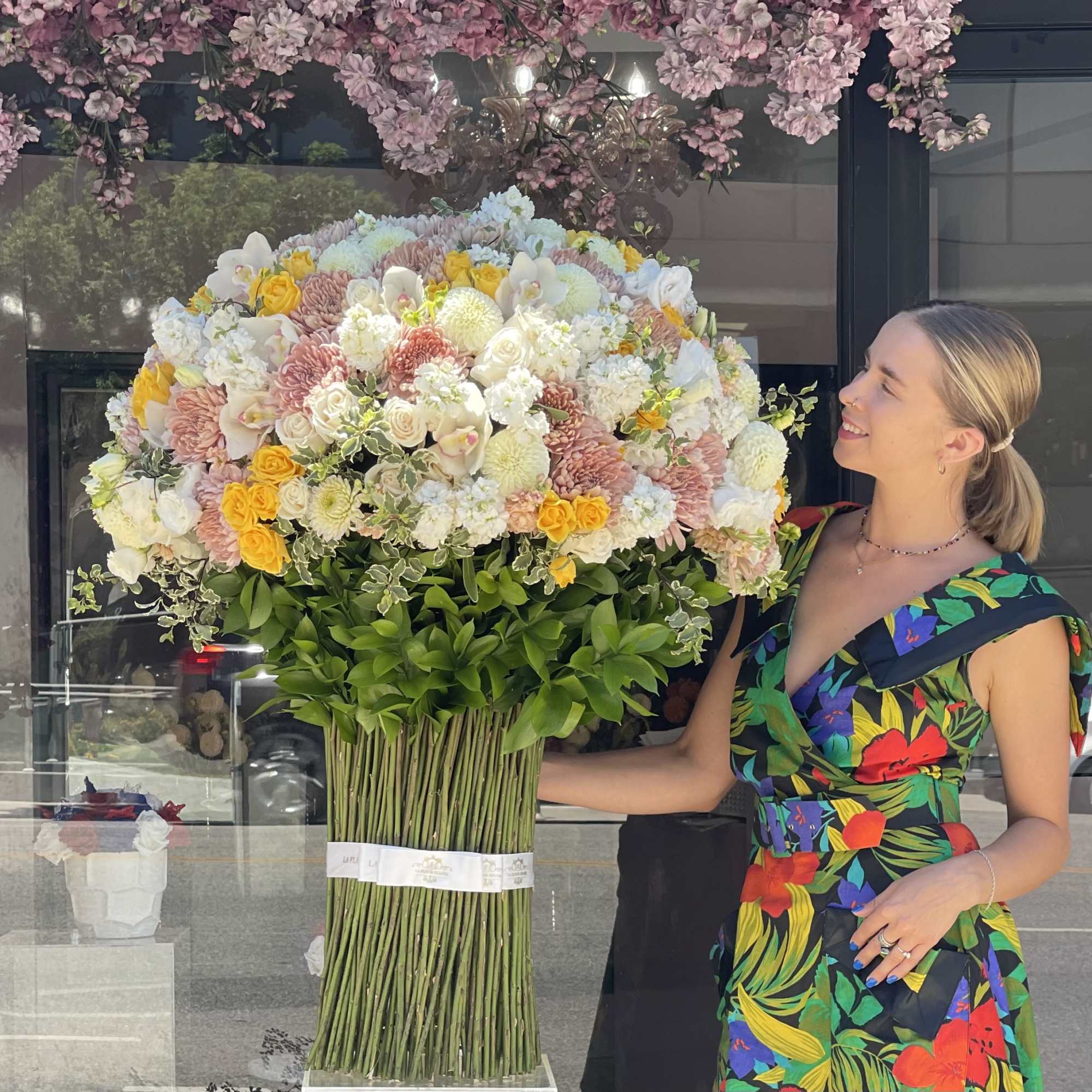 Large pastel floral arrangement with a woman standing beside it