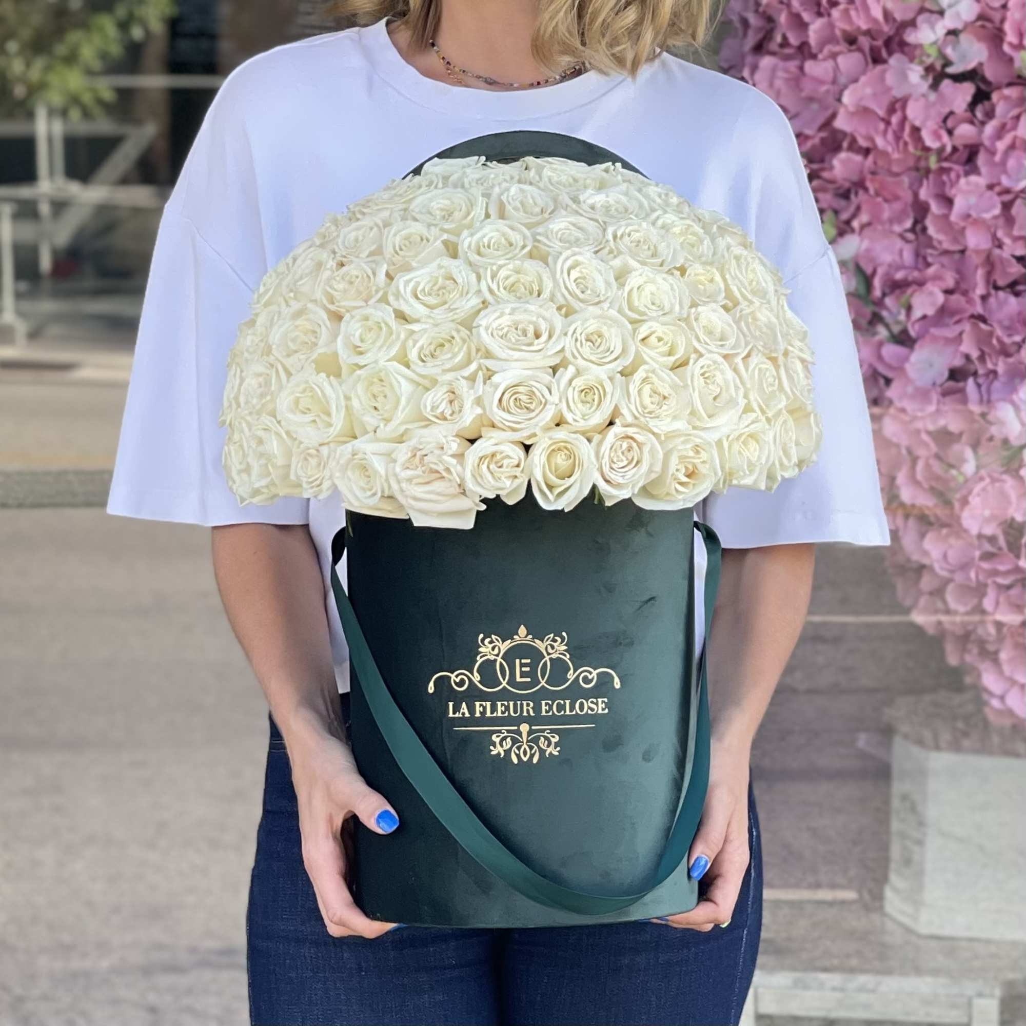 Large bouquet of white roses in a dark green hatbox