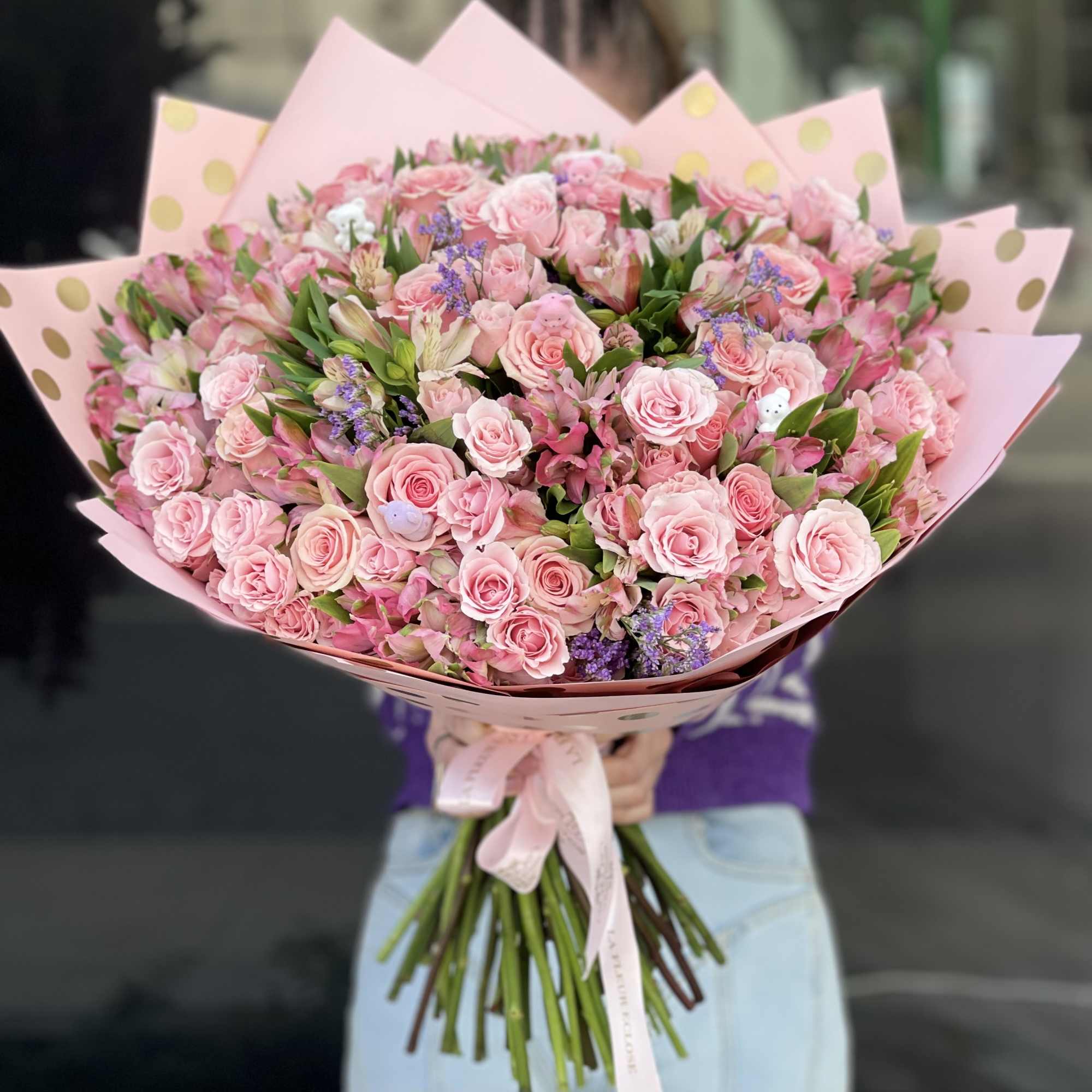 Large bouquet of pink roses and mixed blooms wrapped in pink paper