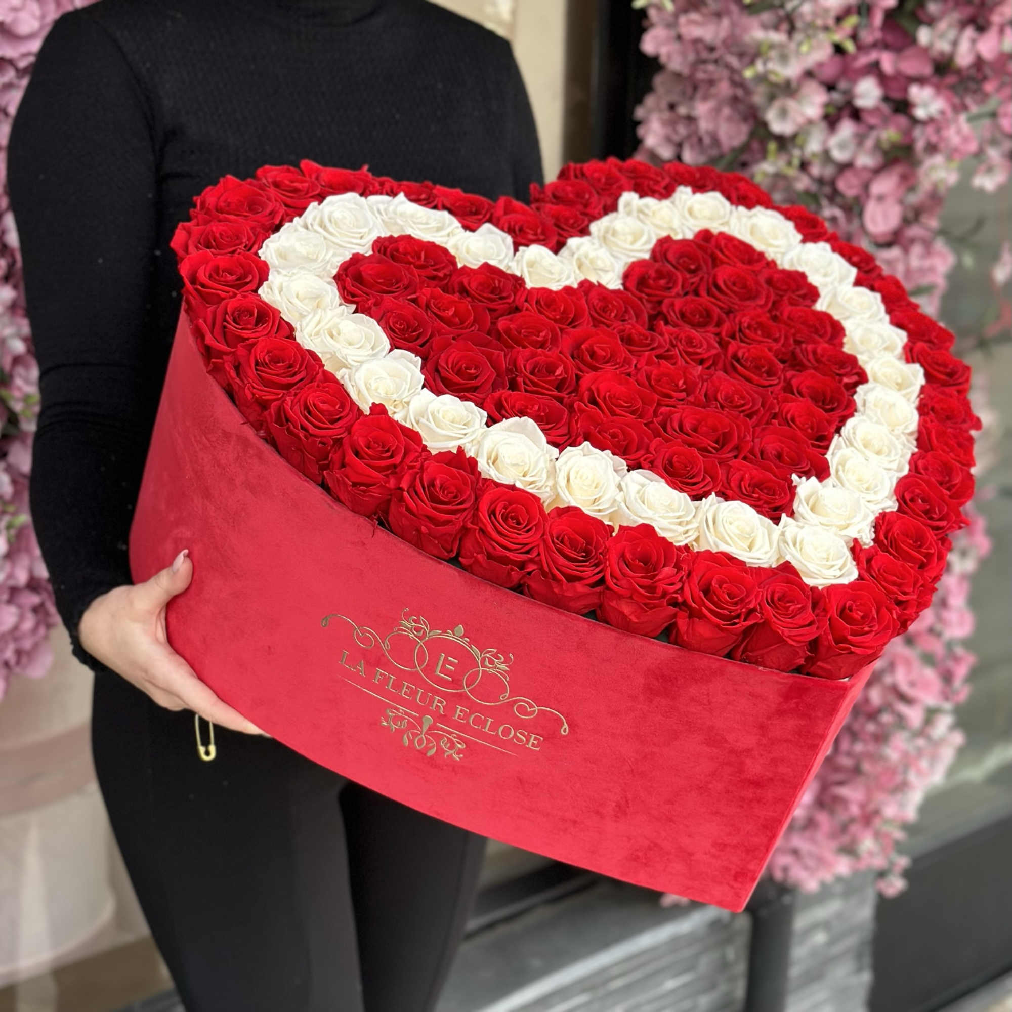 Heart-shaped box of red and white roses being held by a person