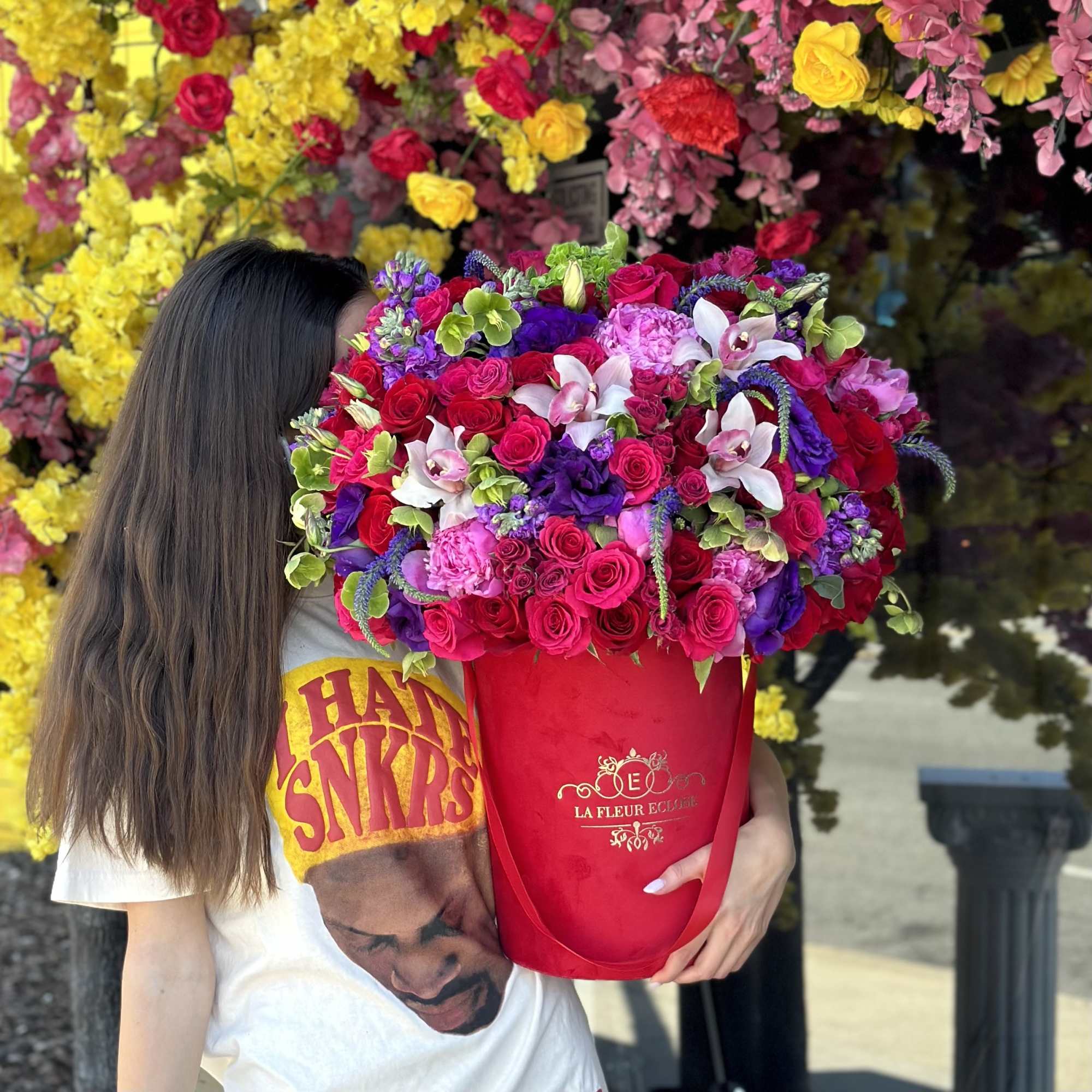 Large mixed bouquet in a red hatbox held by a person