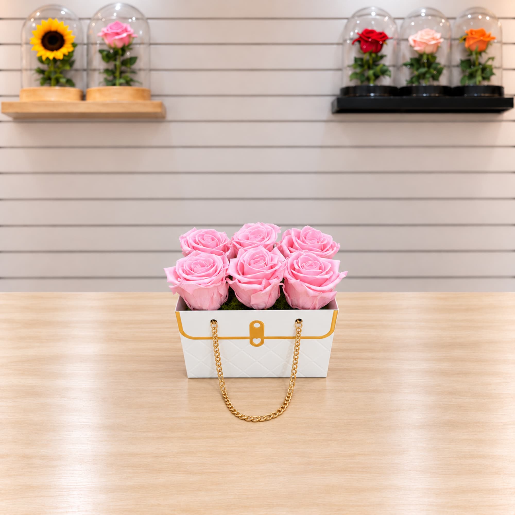 Pink roses in a white handbag-style box with a gold chain handle