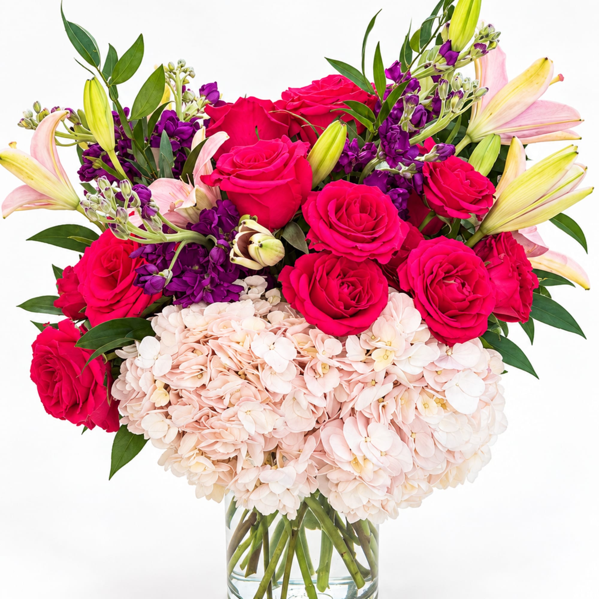 Bouquet of hot pink roses, pale hydrangeas, and lilies in a glass vase