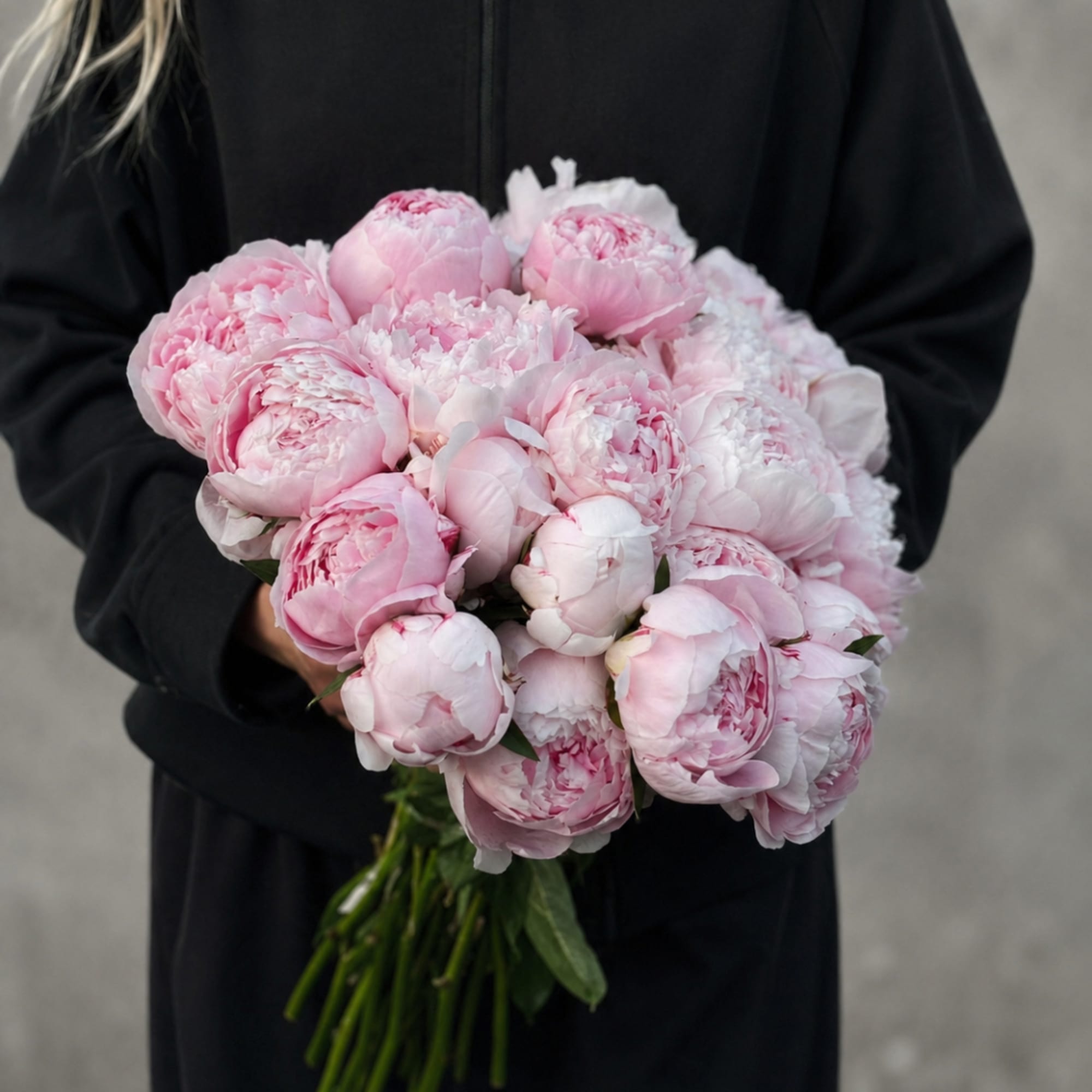 Handheld bouquet of pale pink peonies