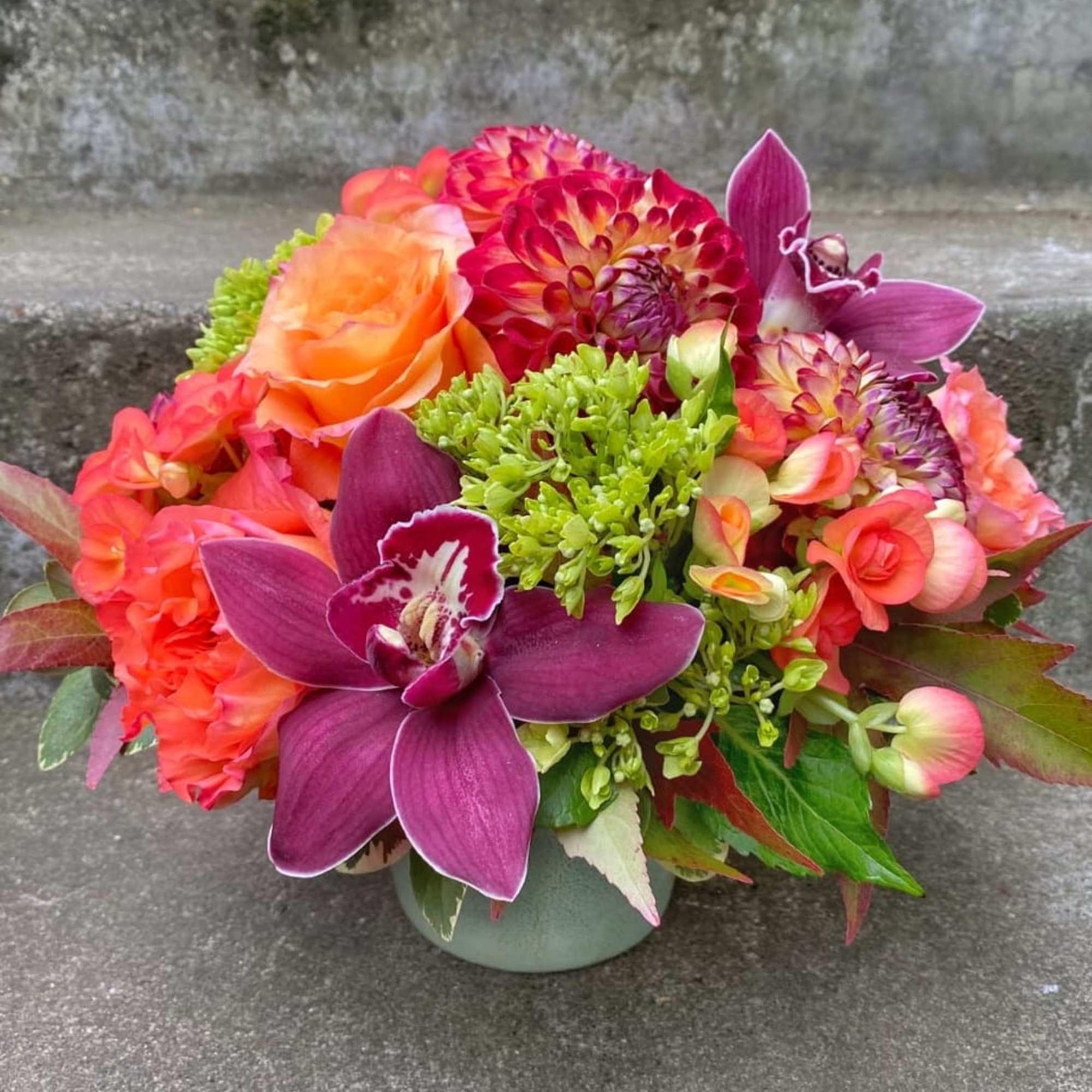Bright mixed bouquet in a low vase with orange, pink, and purple blooms
