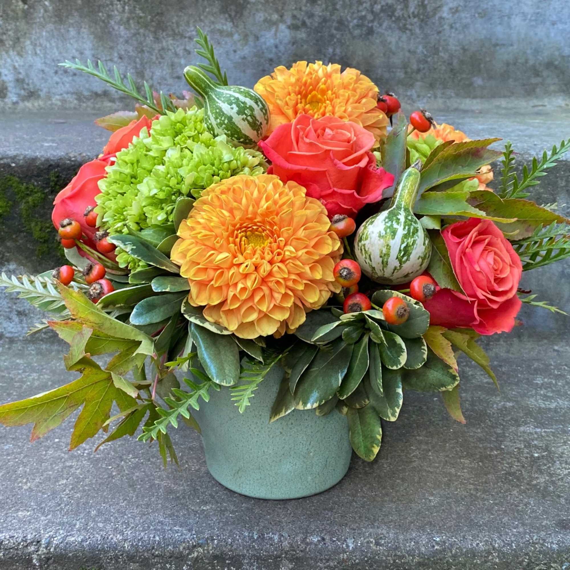 Bouquet of orange dahlias and pink roses in a green vase