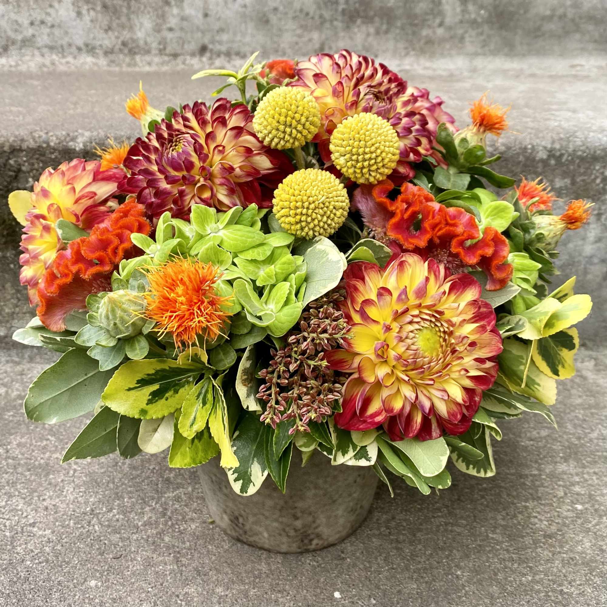 Colorful mixed bouquet in a gray pot with orange and yellow blooms