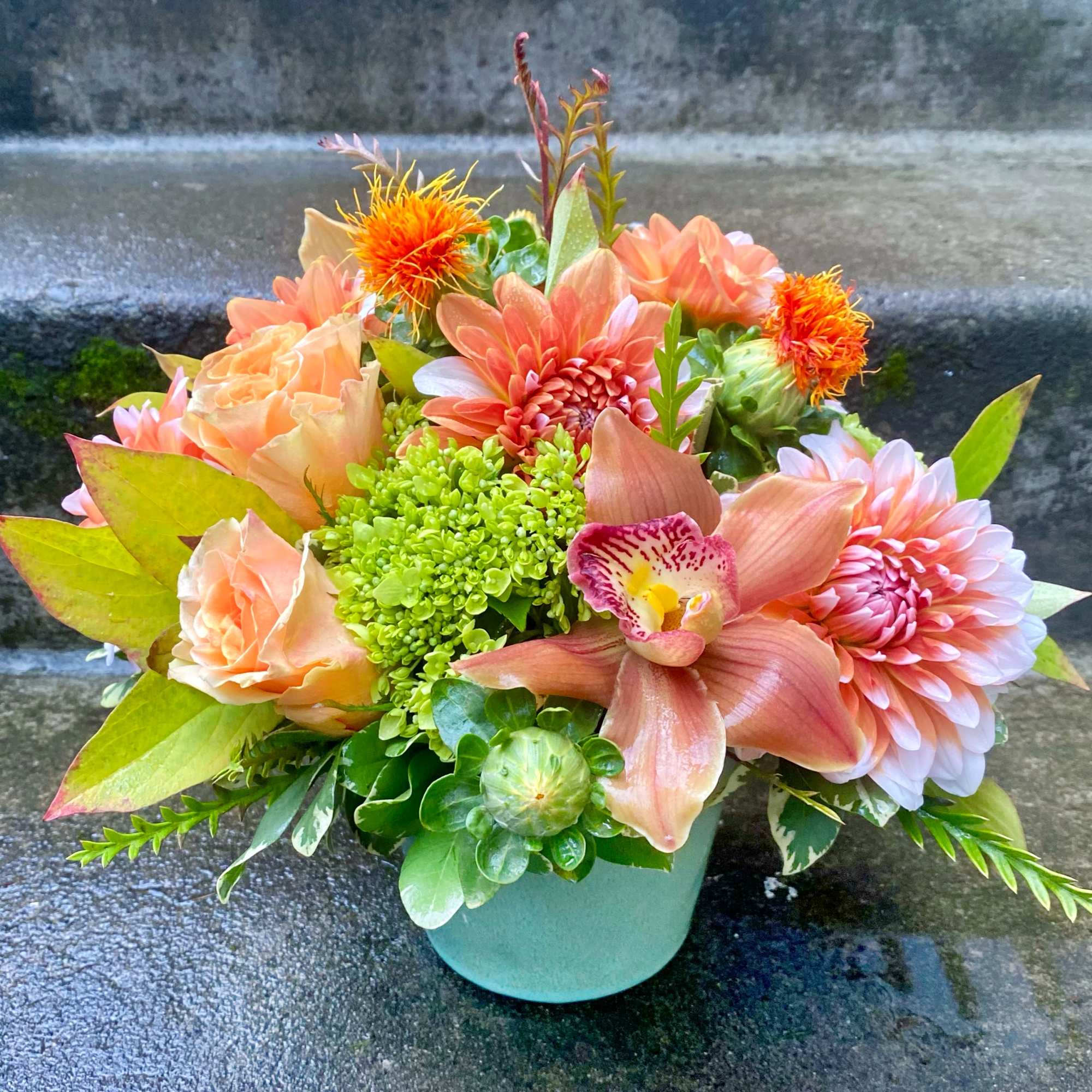 Peach and pink flower arrangement in a light blue vase