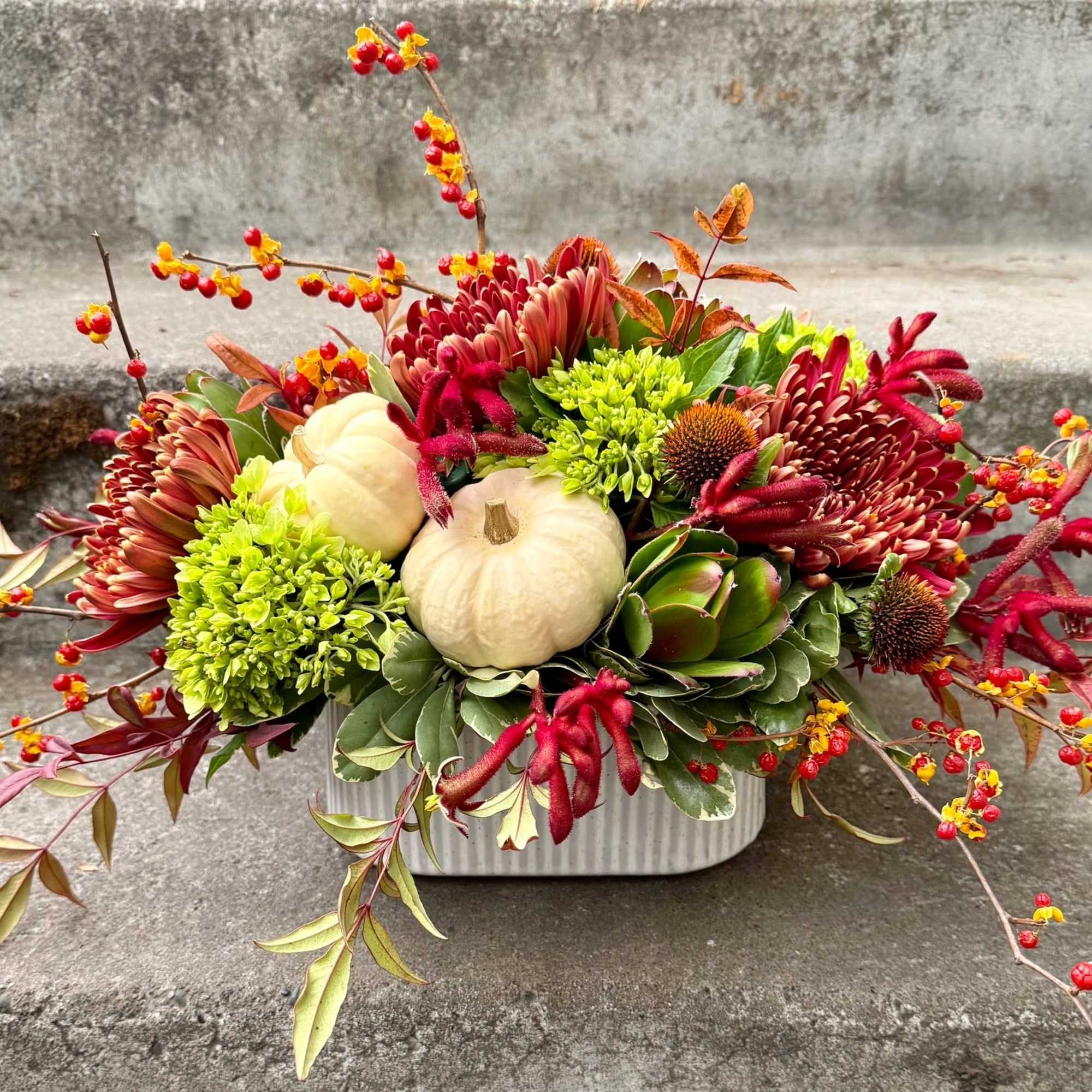 Autumn floral arrangement with pumpkins in a white container