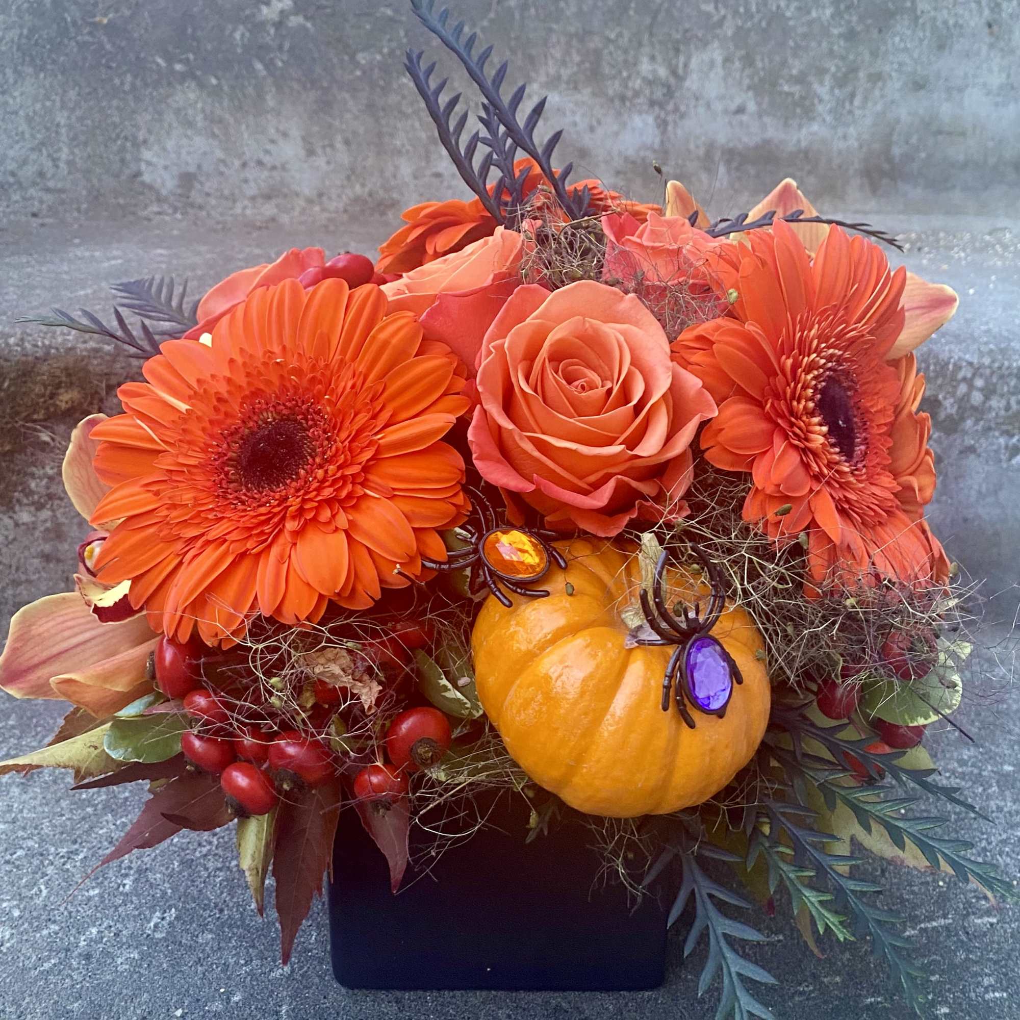 Orange floral arrangement with gerbera daisies, roses, and a small pumpkin