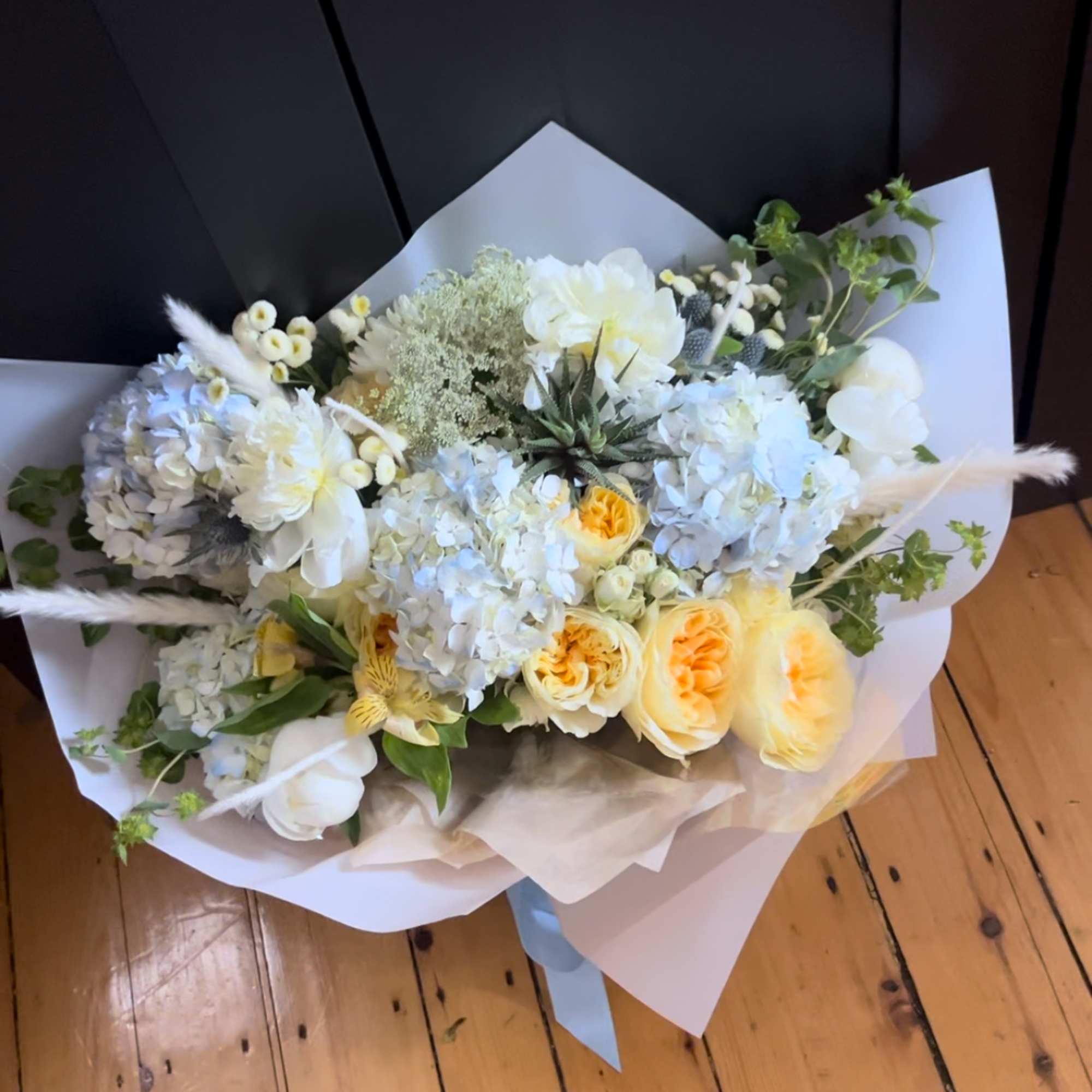 Bouquet of white and pale yellow flowers wrapped in white paper
