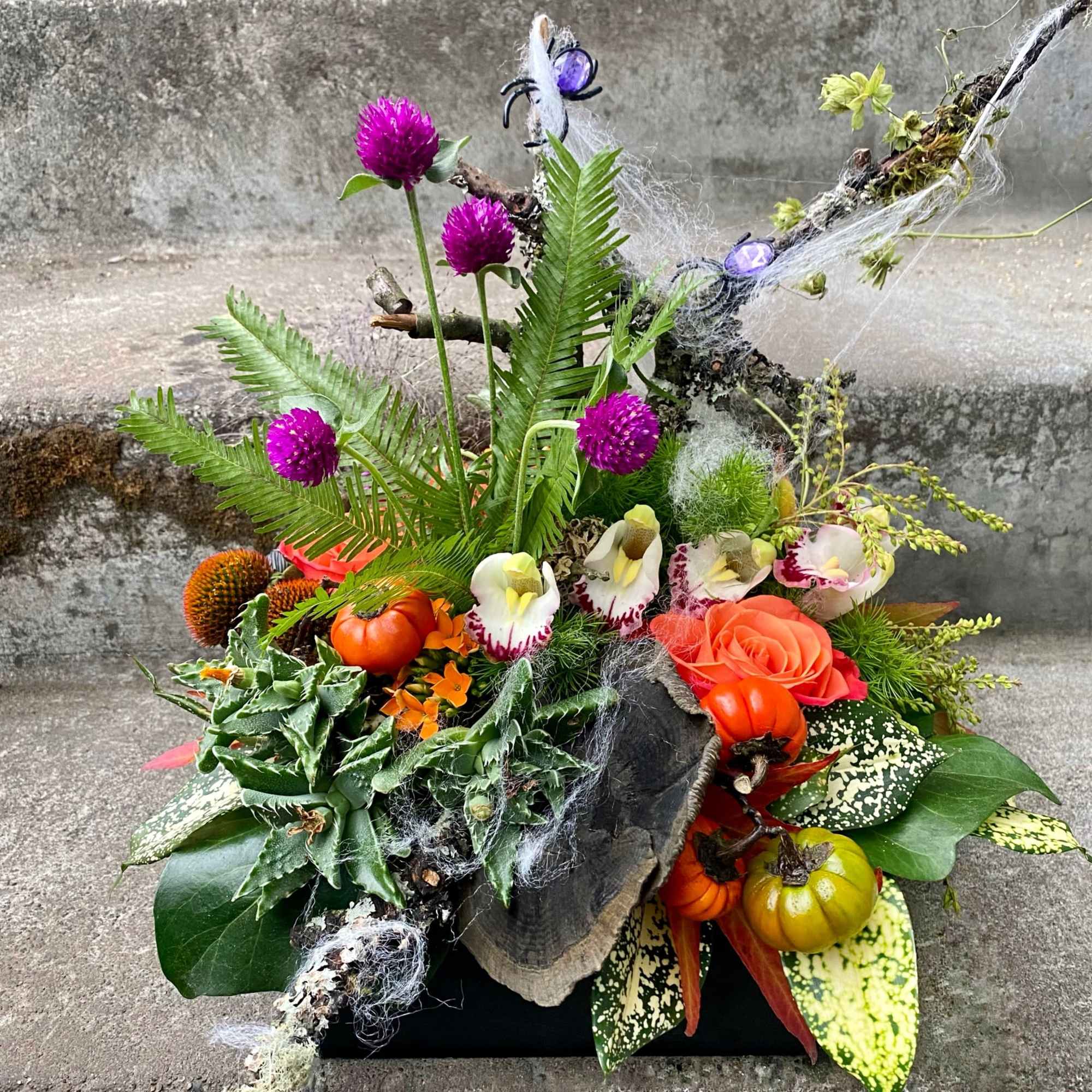 Halloween floral arrangement with orange roses, pumpkins, and purple blooms