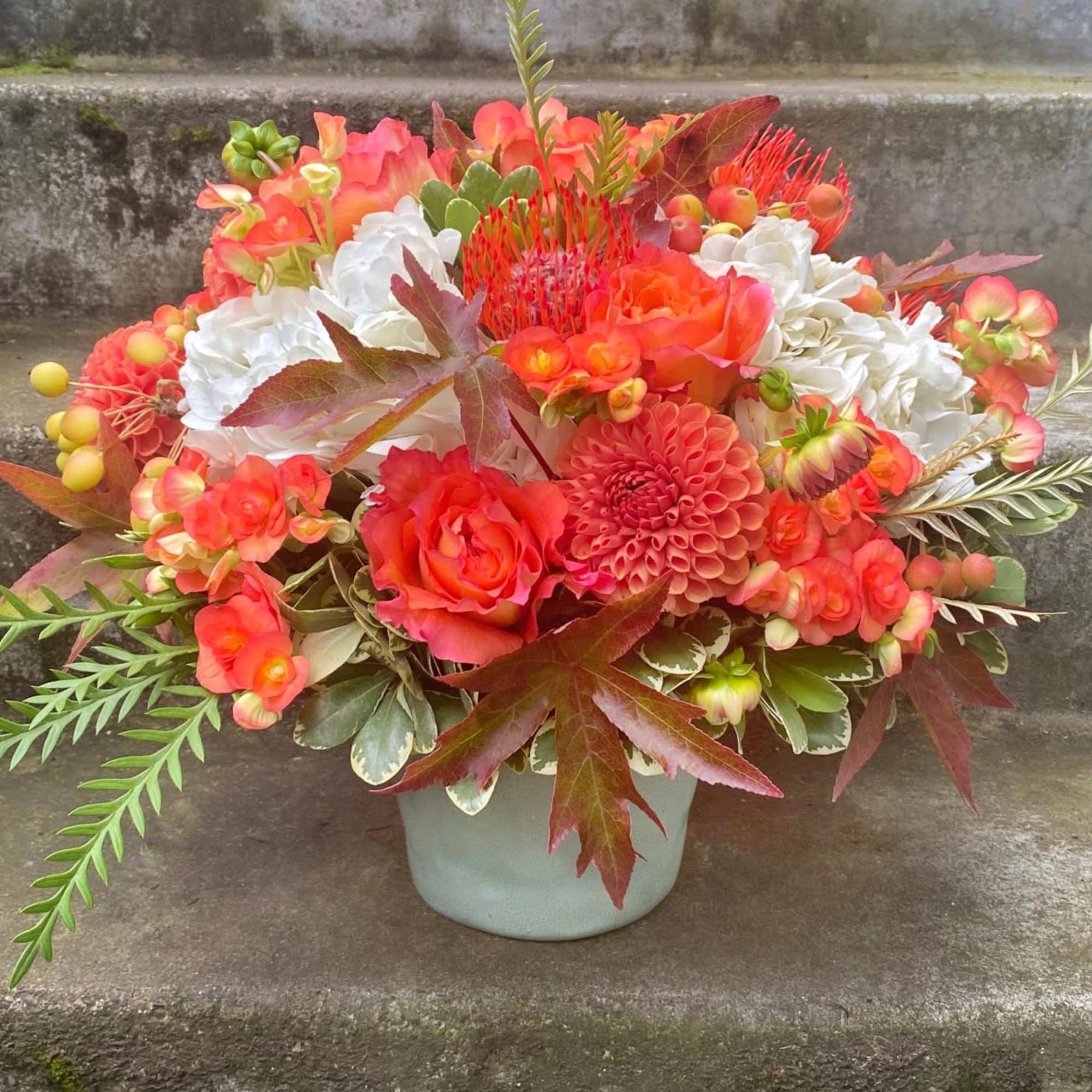 Orange and white floral arrangement in a pale vase