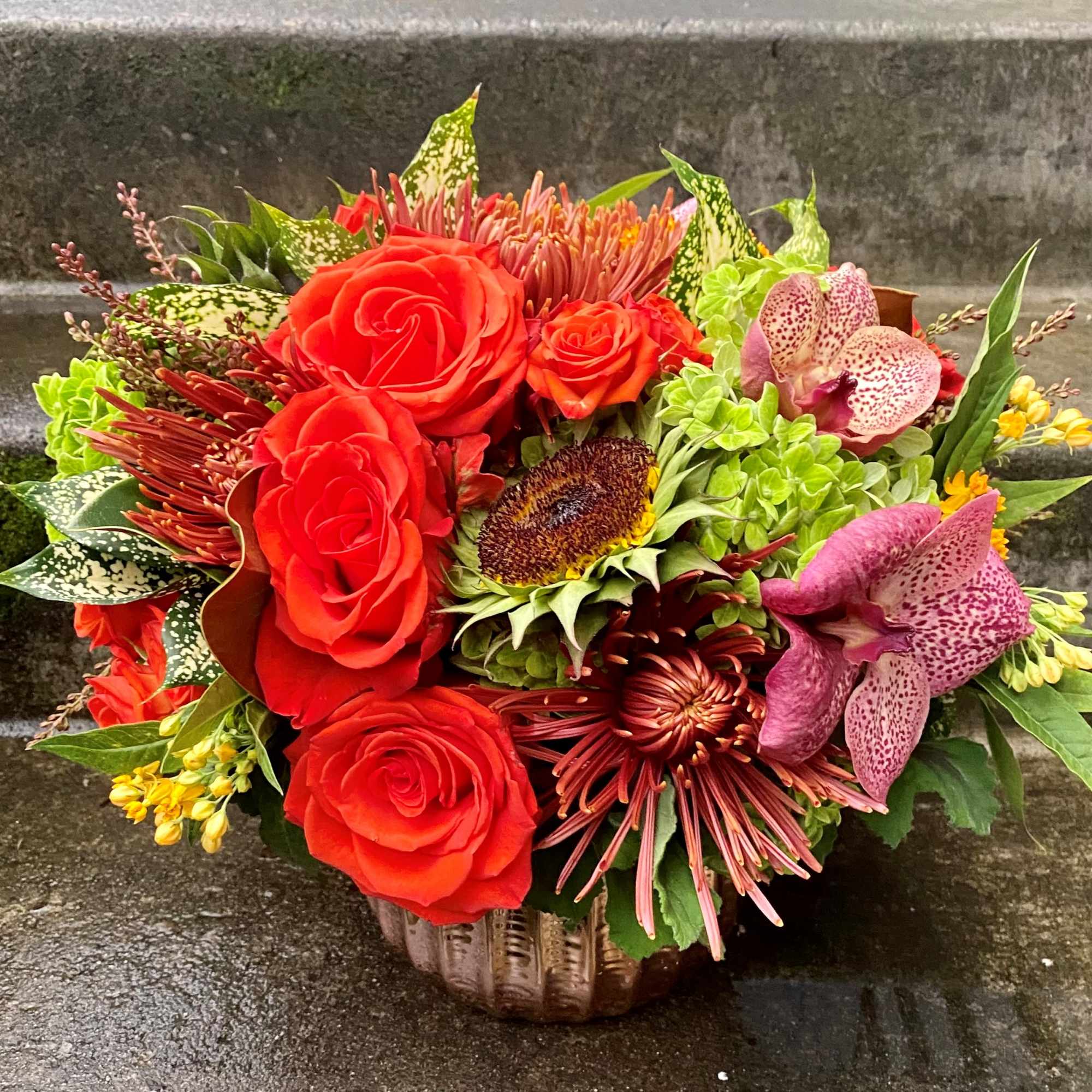 Red roses and pink orchids in a low basket arrangement