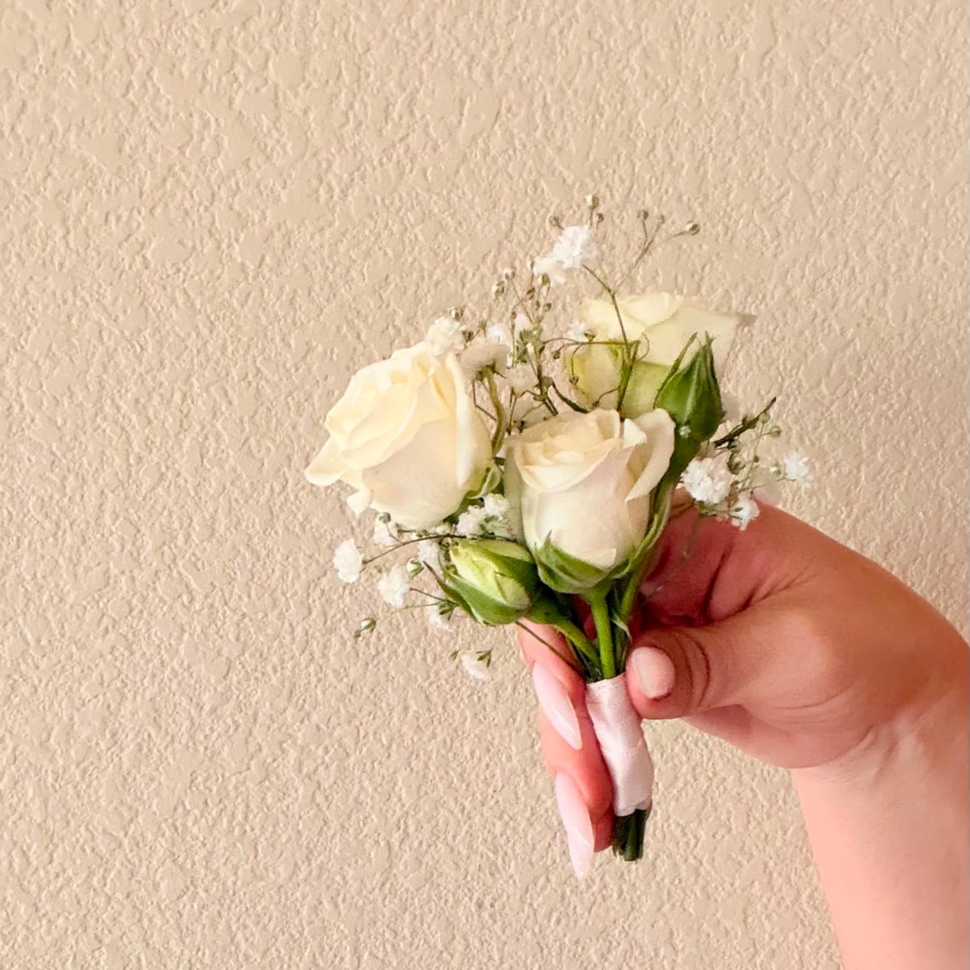 Handheld boutonniere with white roses and baby's breath