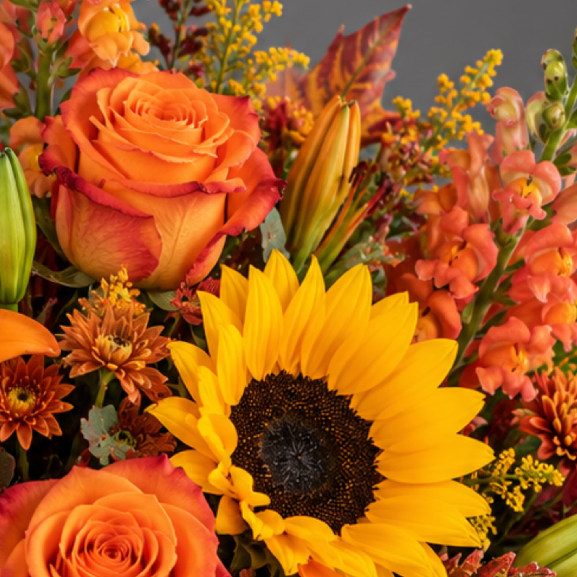 Orange roses and a sunflower in a mixed bouquet