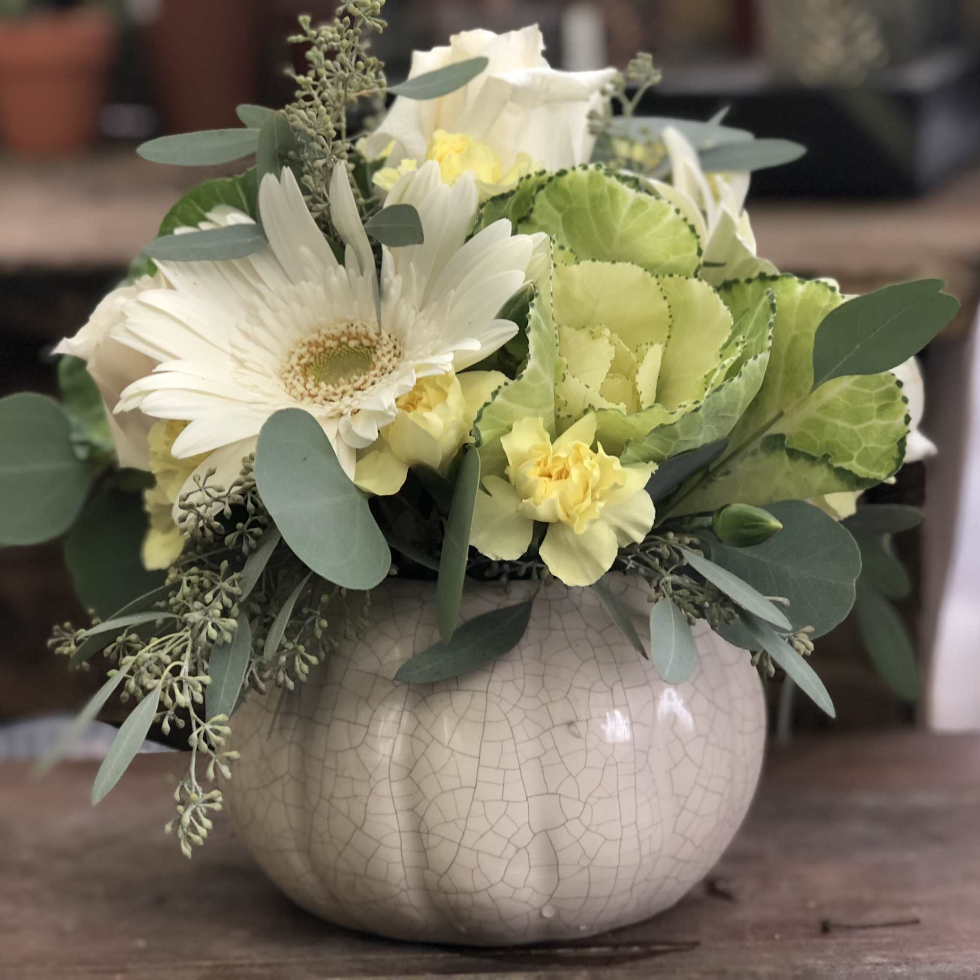 White and pale yellow floral arrangement in a round ceramic vase