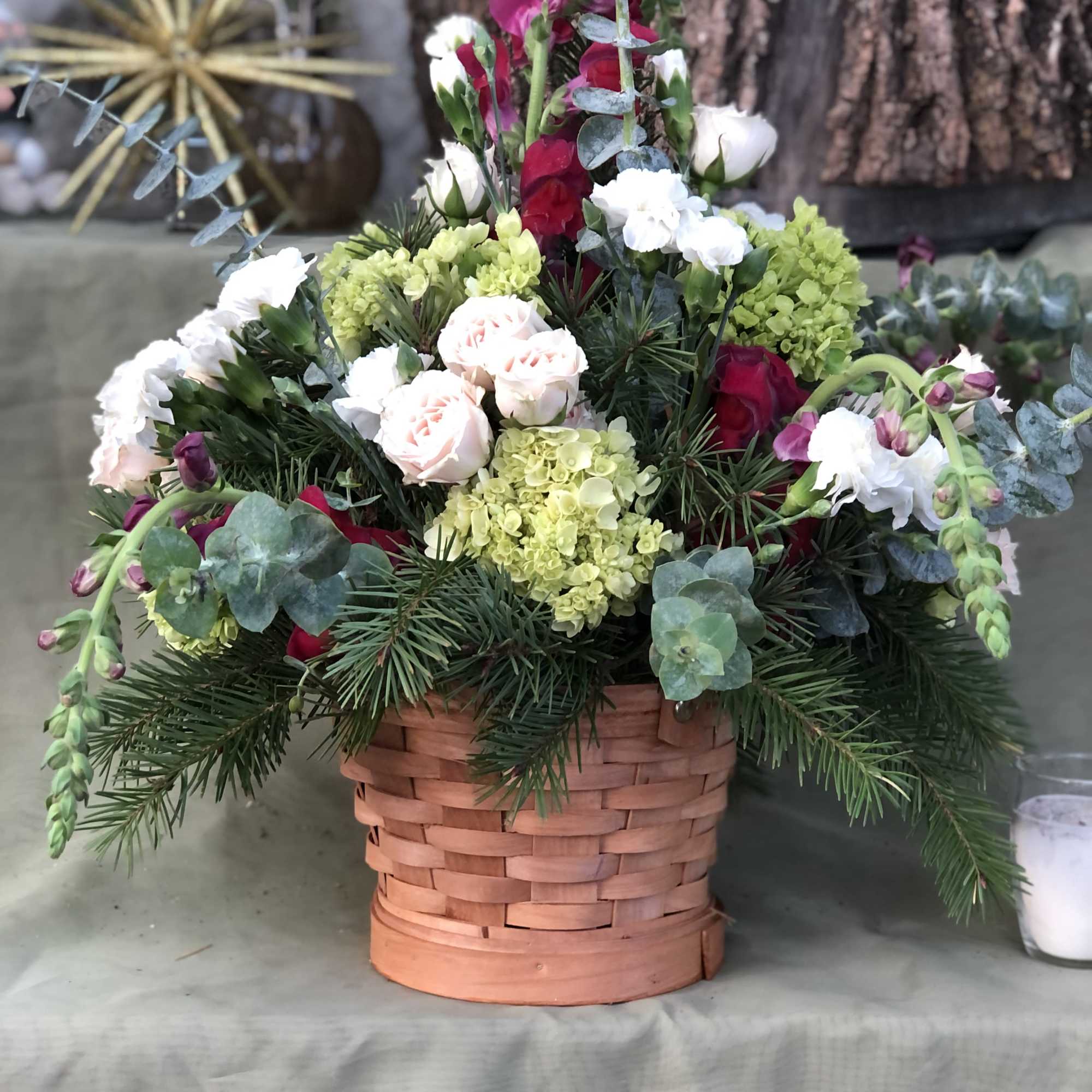 Basket arrangement of red, white, and green flowers with pine branches