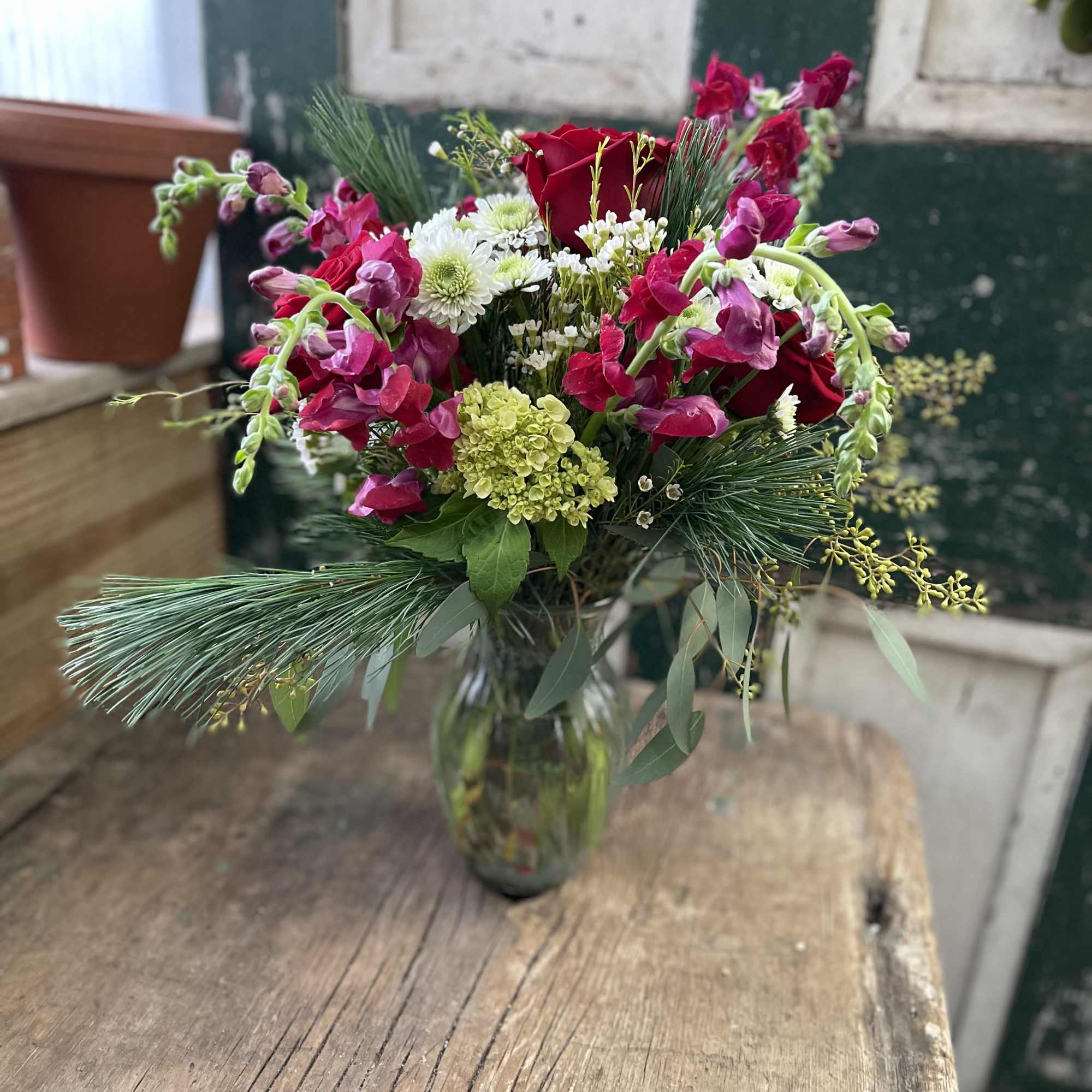Bouquet of red roses and pink snapdragons in a glass vase