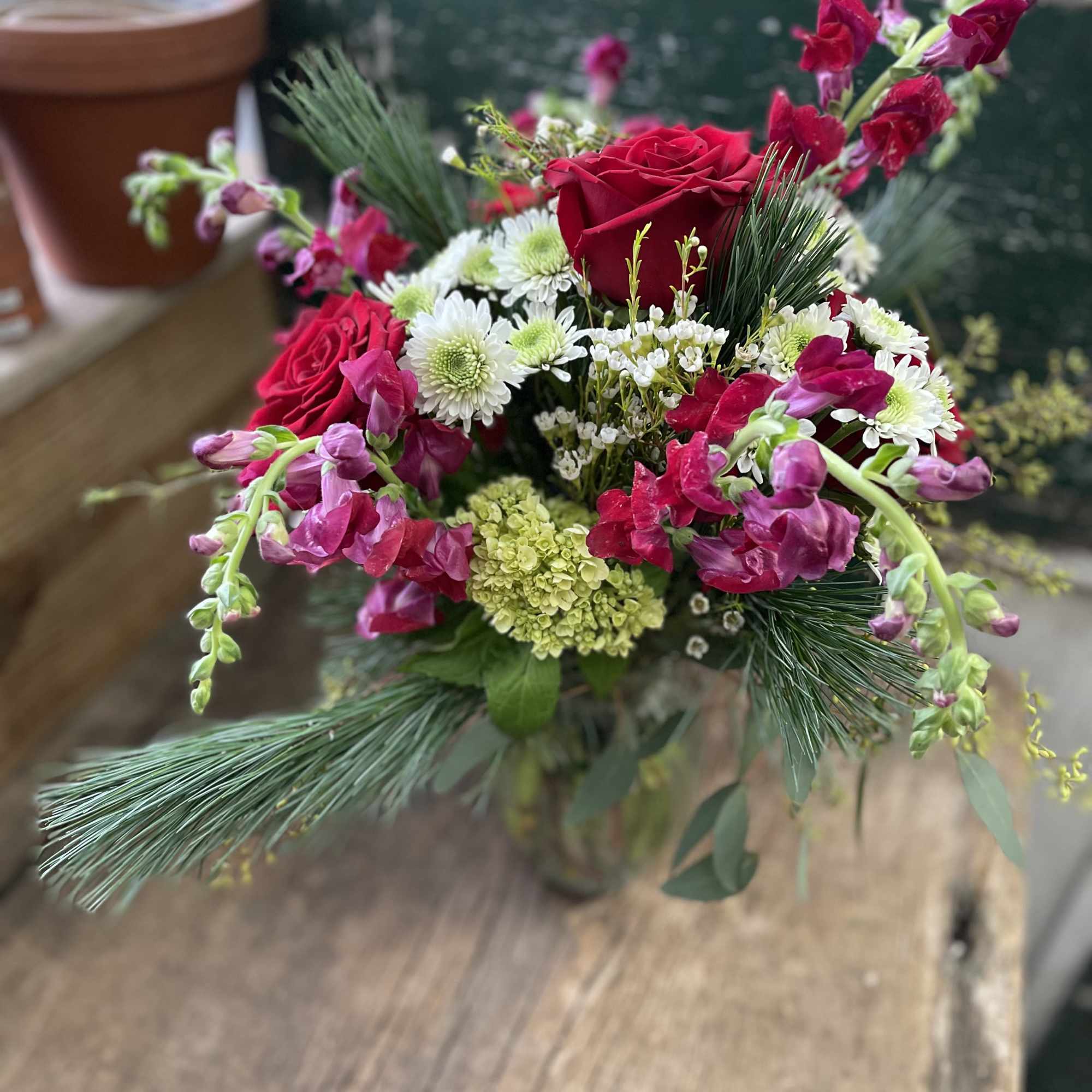 Bouquet of red roses, pink snapdragons, and white daisies in a vase
