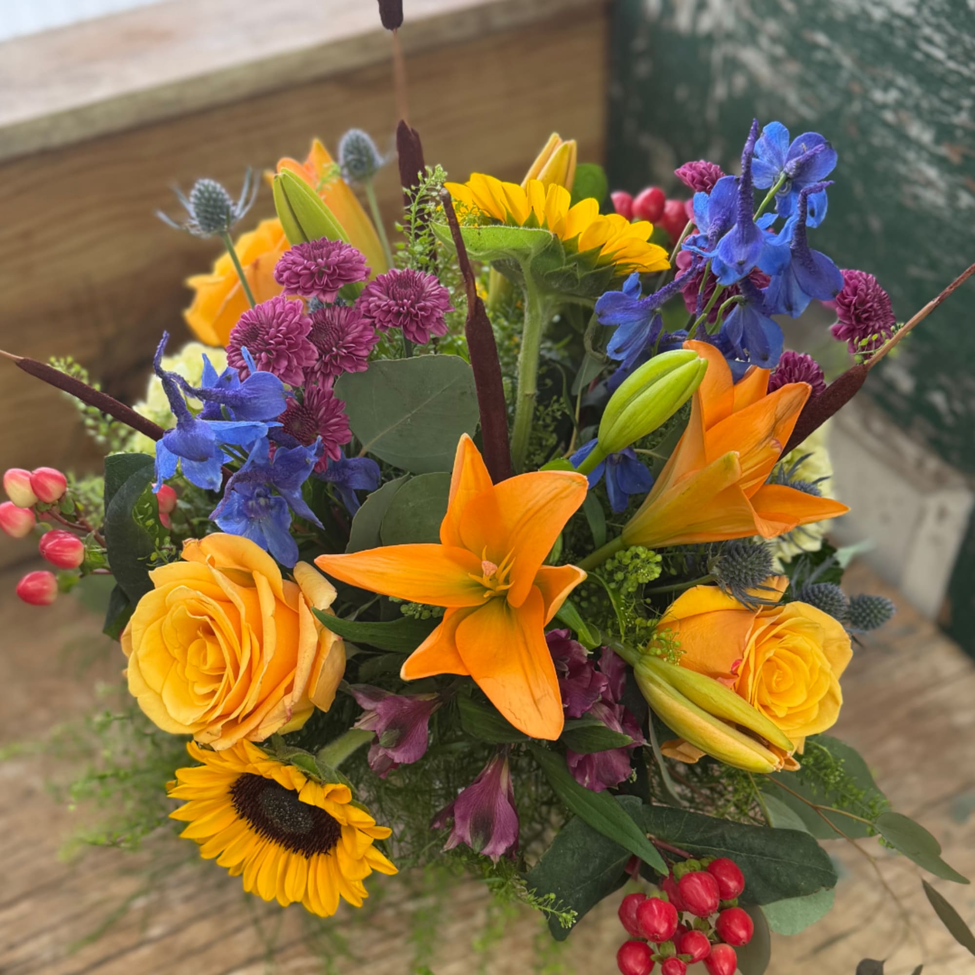 Colorful bouquet with lilies, roses, sunflowers, and blue flowers