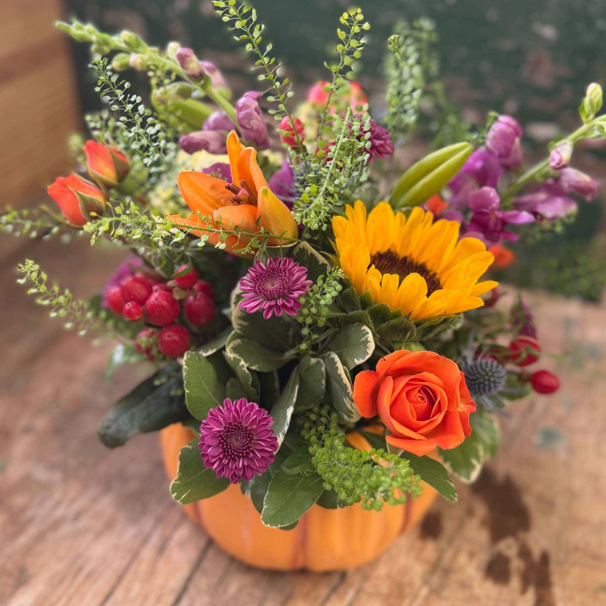Mixed bouquet in a pumpkin-shaped orange container with sunflowers and roses