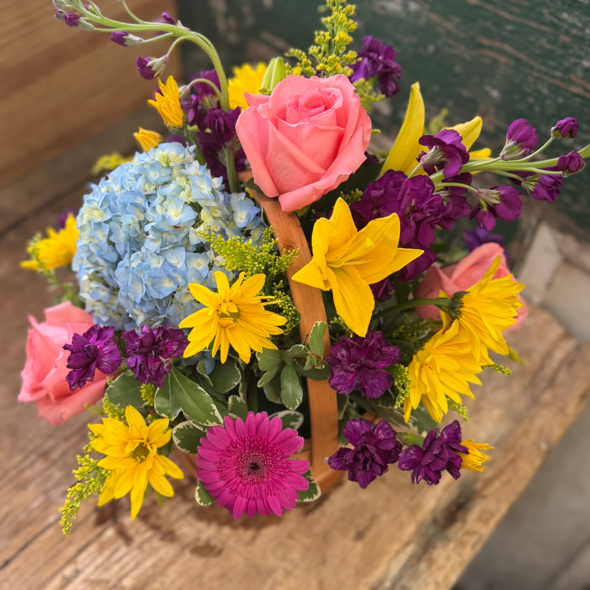 Mixed bouquet with pink roses, blue hydrangea, yellow daisies, and purple flowers