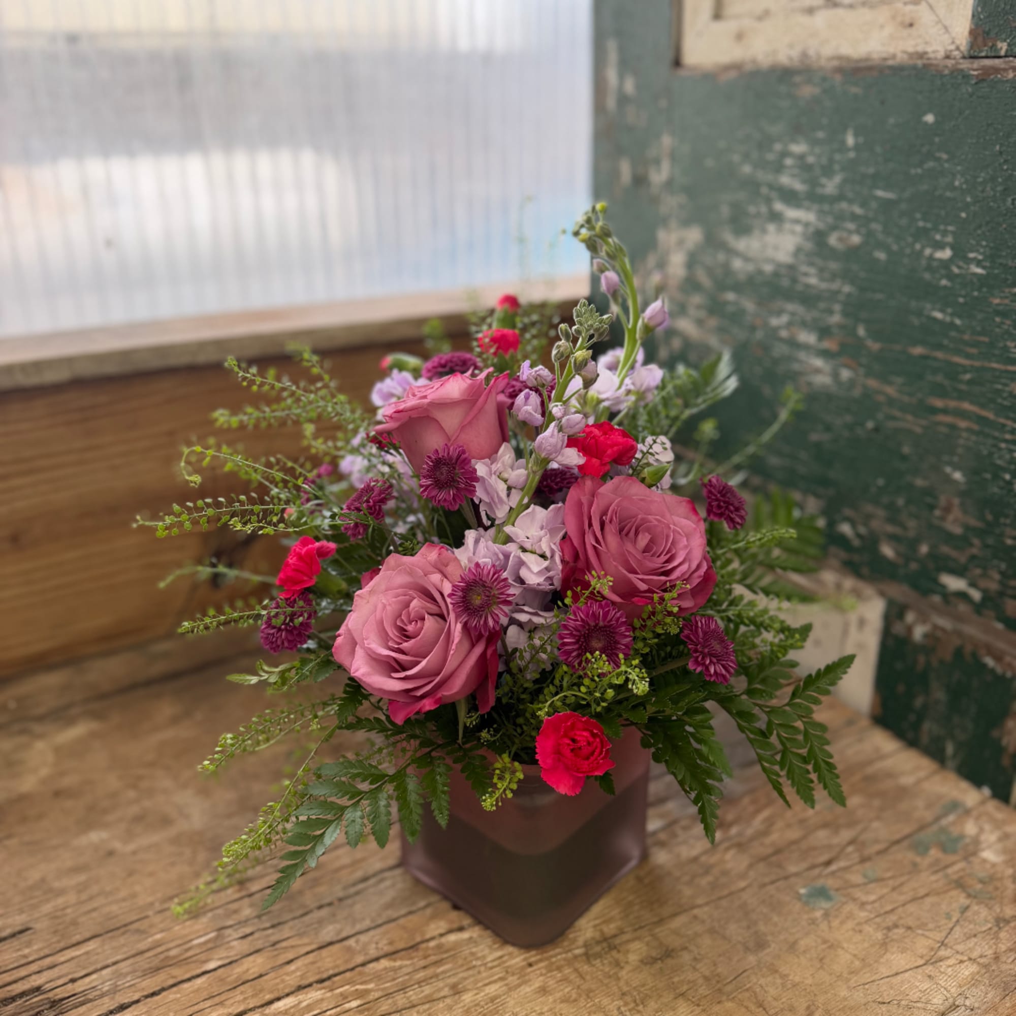 Pink and purple mixed bouquet in a square vase