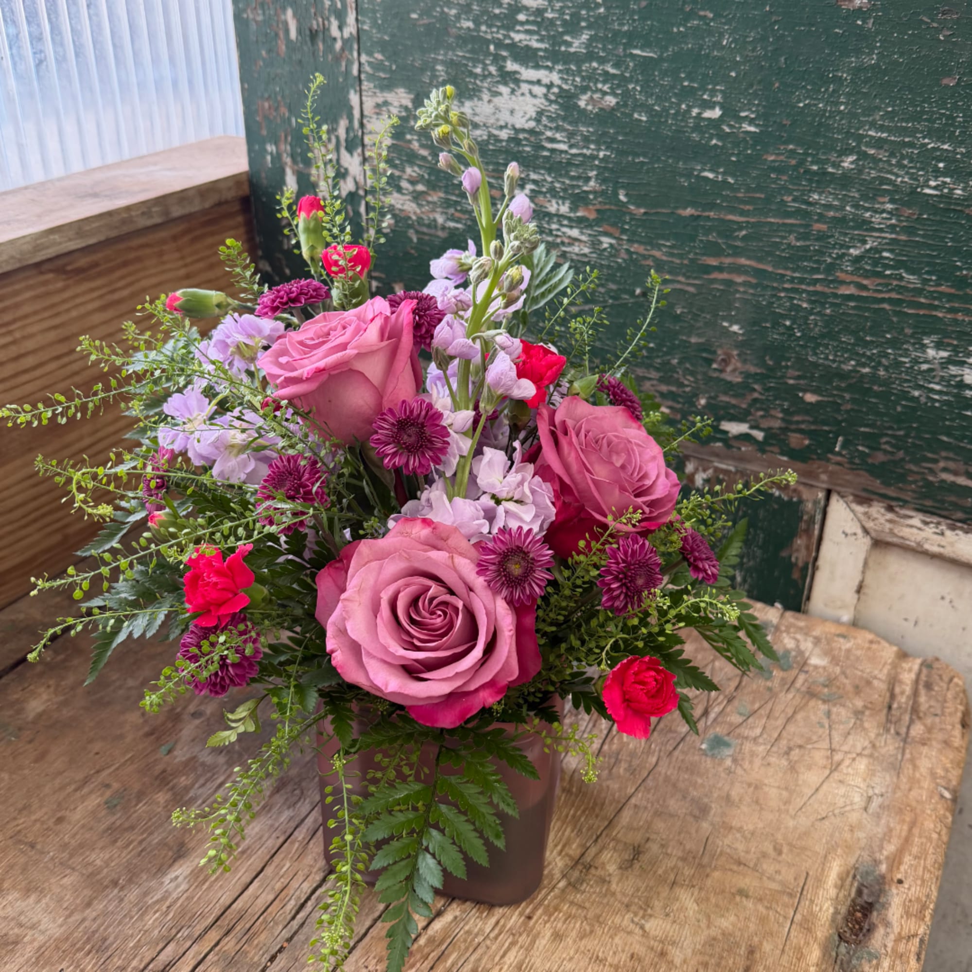 Pink and purple mixed flower arrangement in a square vase