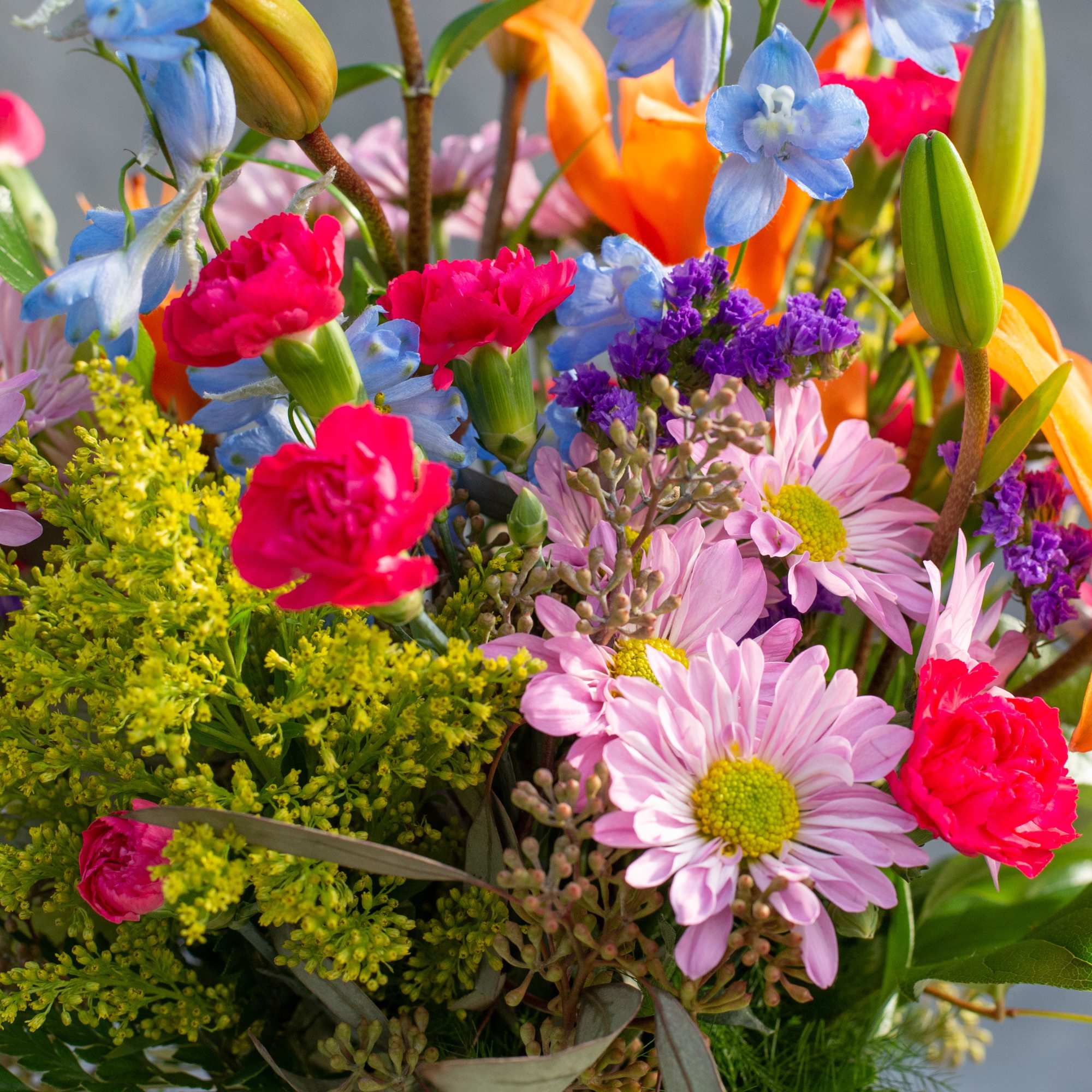 Colorful mixed bouquet with pink daisies, carnations, and blue flowers