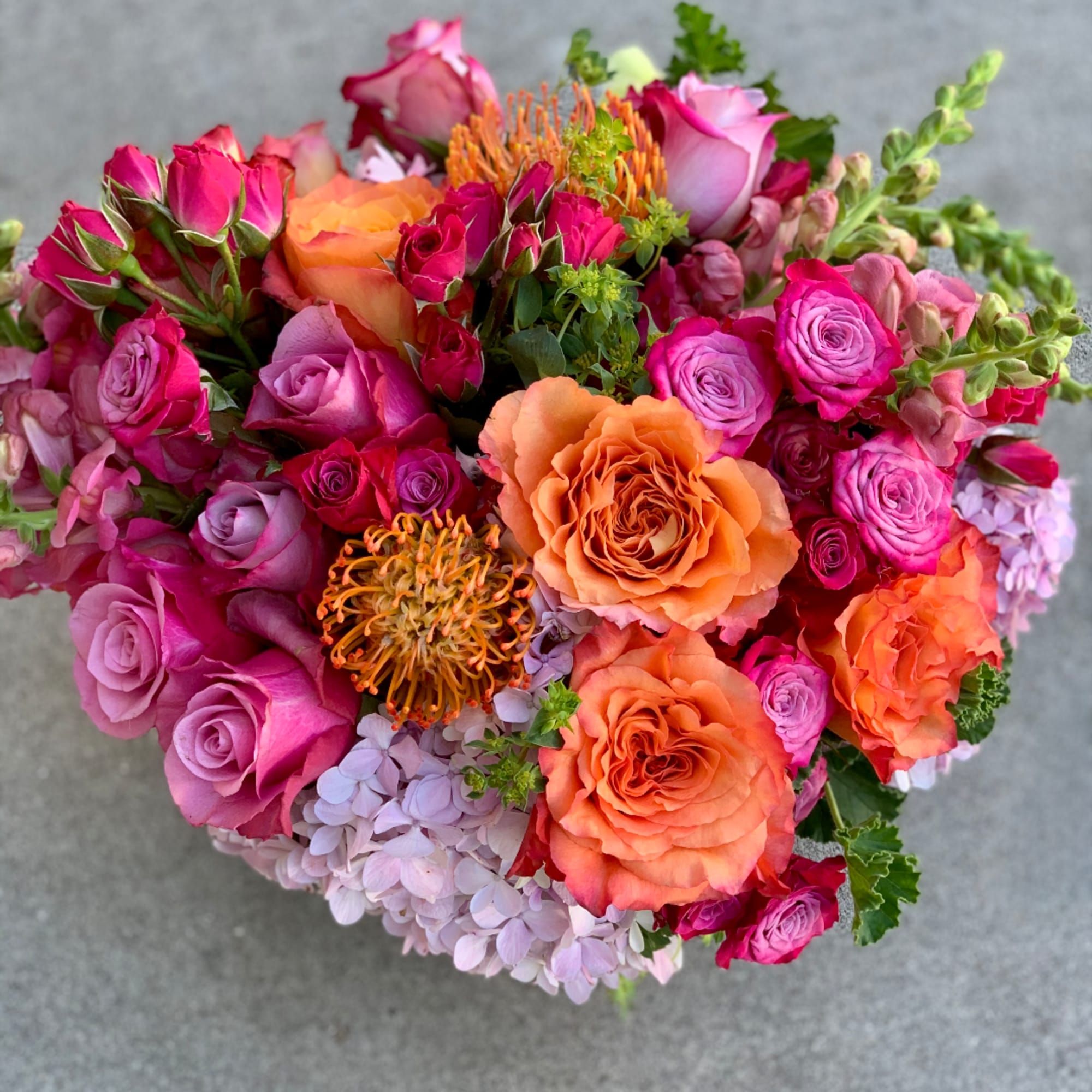 Bouquet of pink and orange roses with lavender hydrangea and orange pincushion blooms