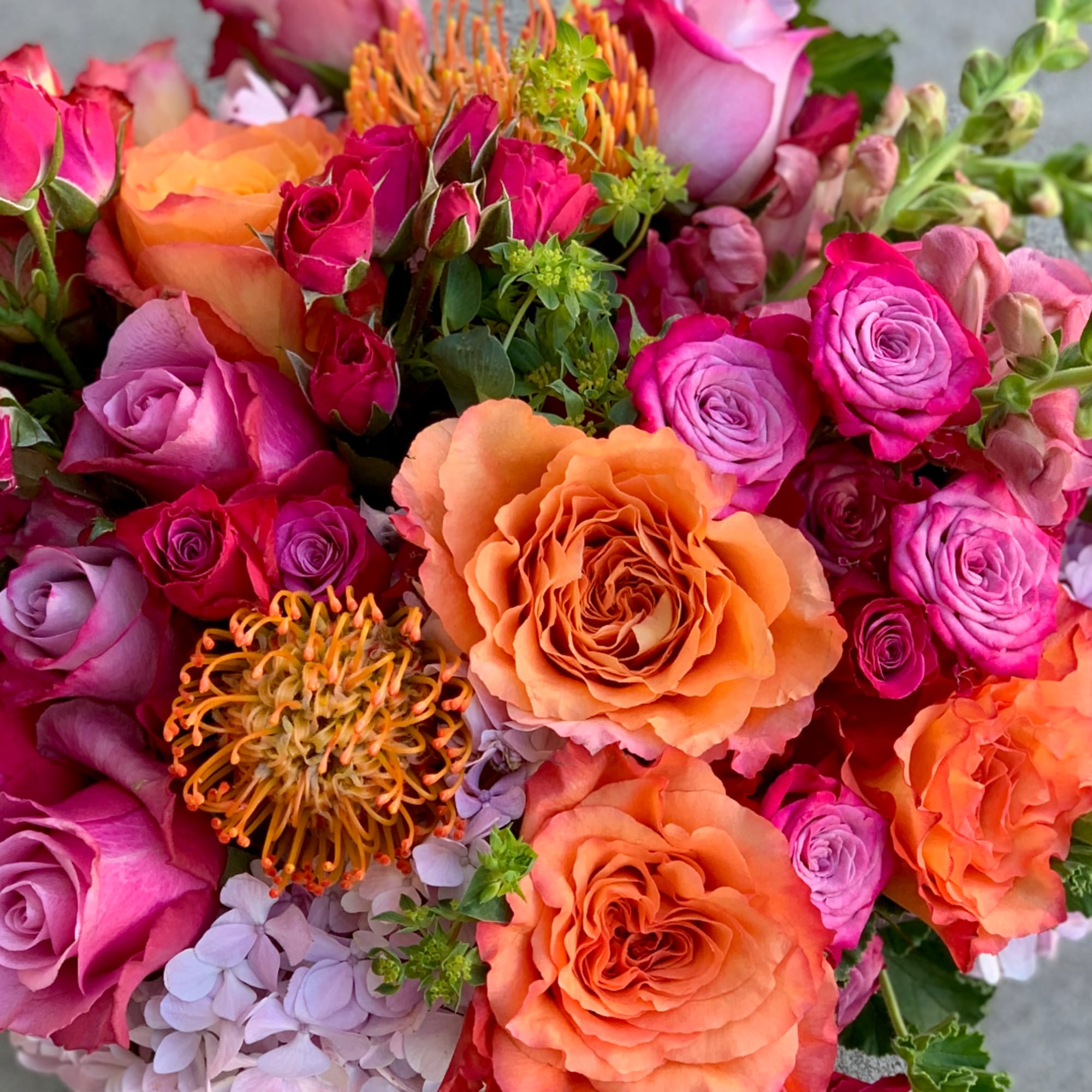 Bouquet of orange, pink, and lavender roses with mixed blooms
