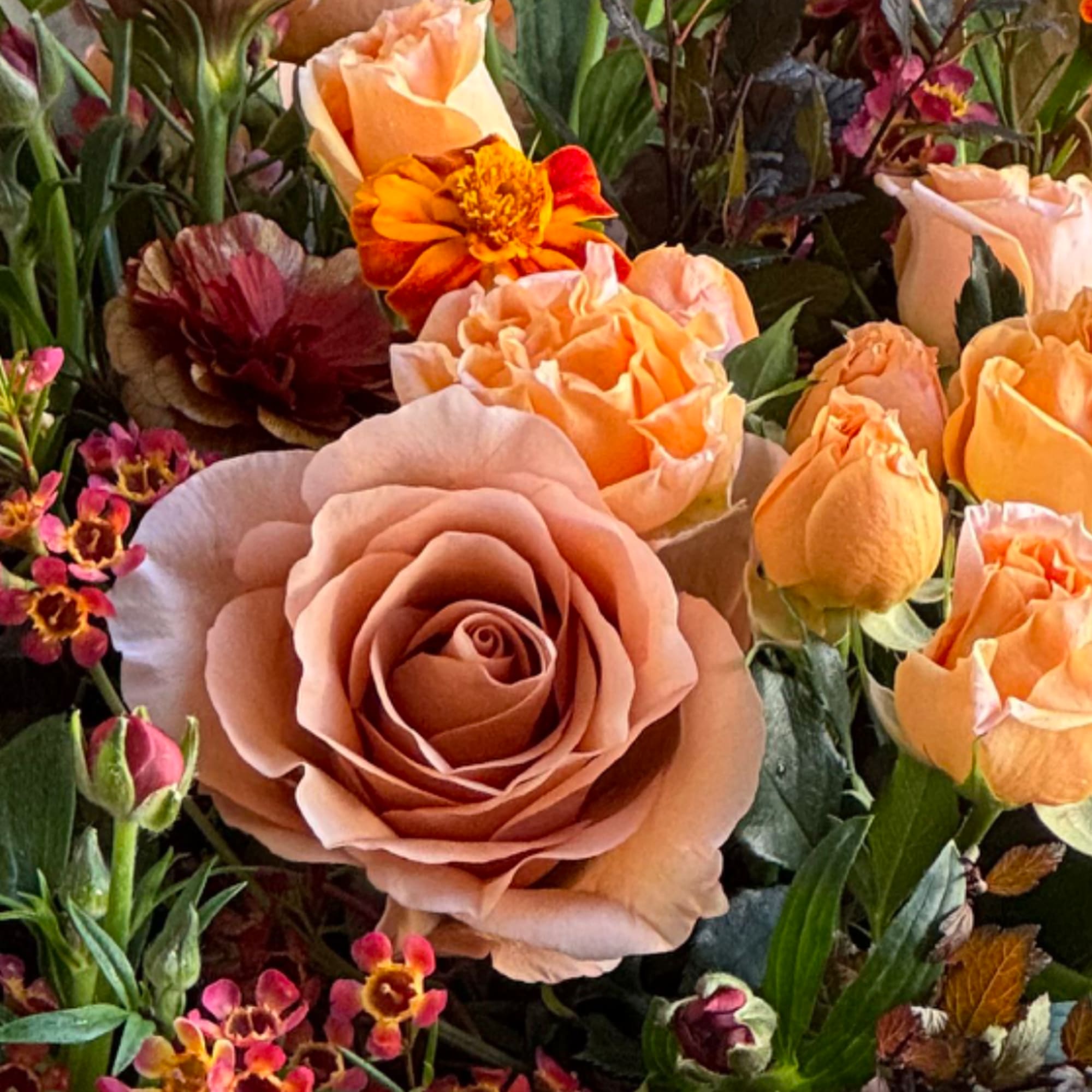 Peach roses and orange flowers in a mixed bouquet
