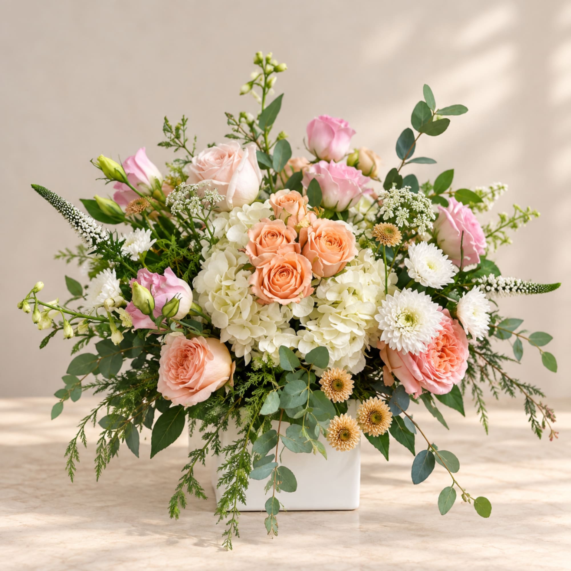 Mixed bouquet of peach and pink roses in a white vase