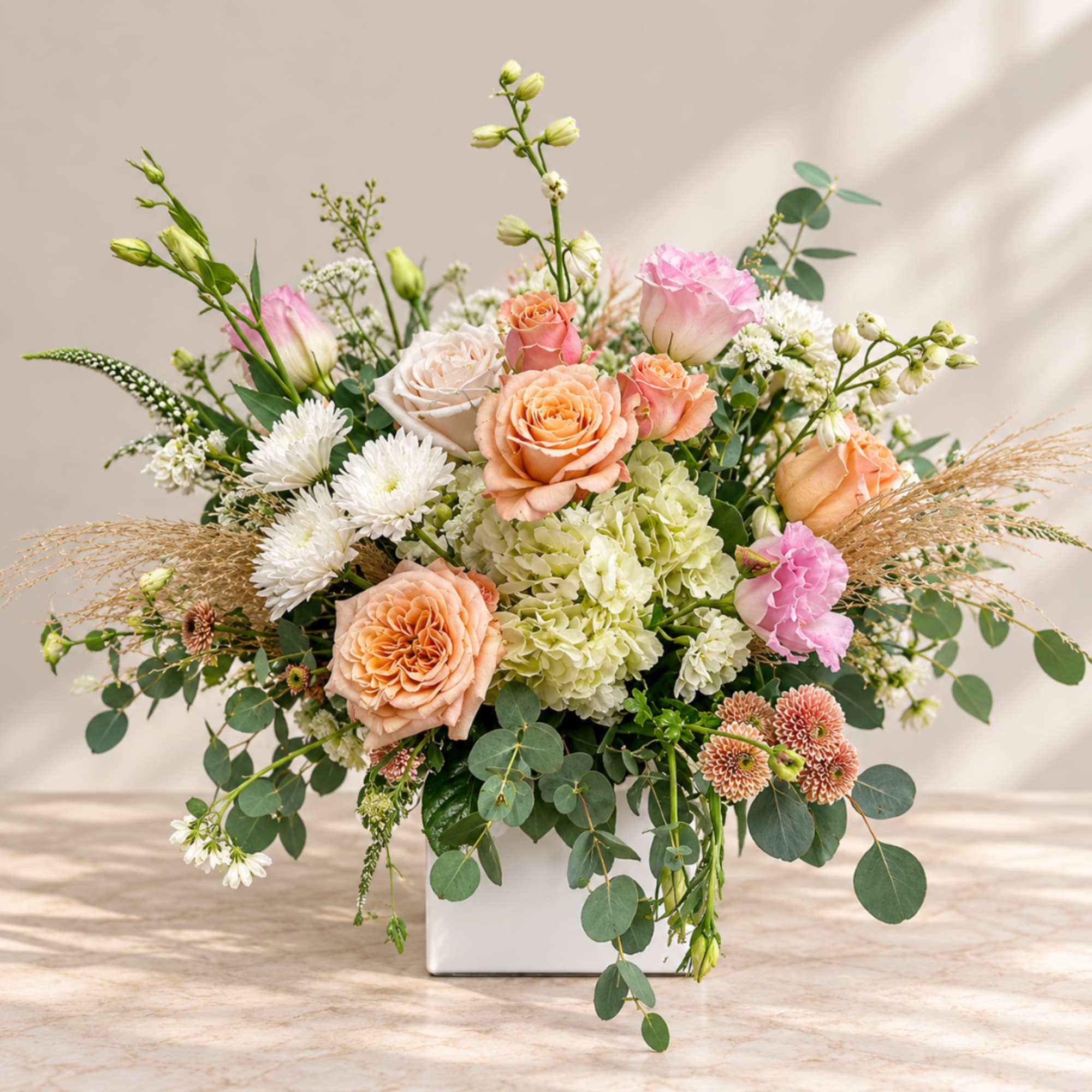Mixed bouquet of peach and pink roses in a white vase