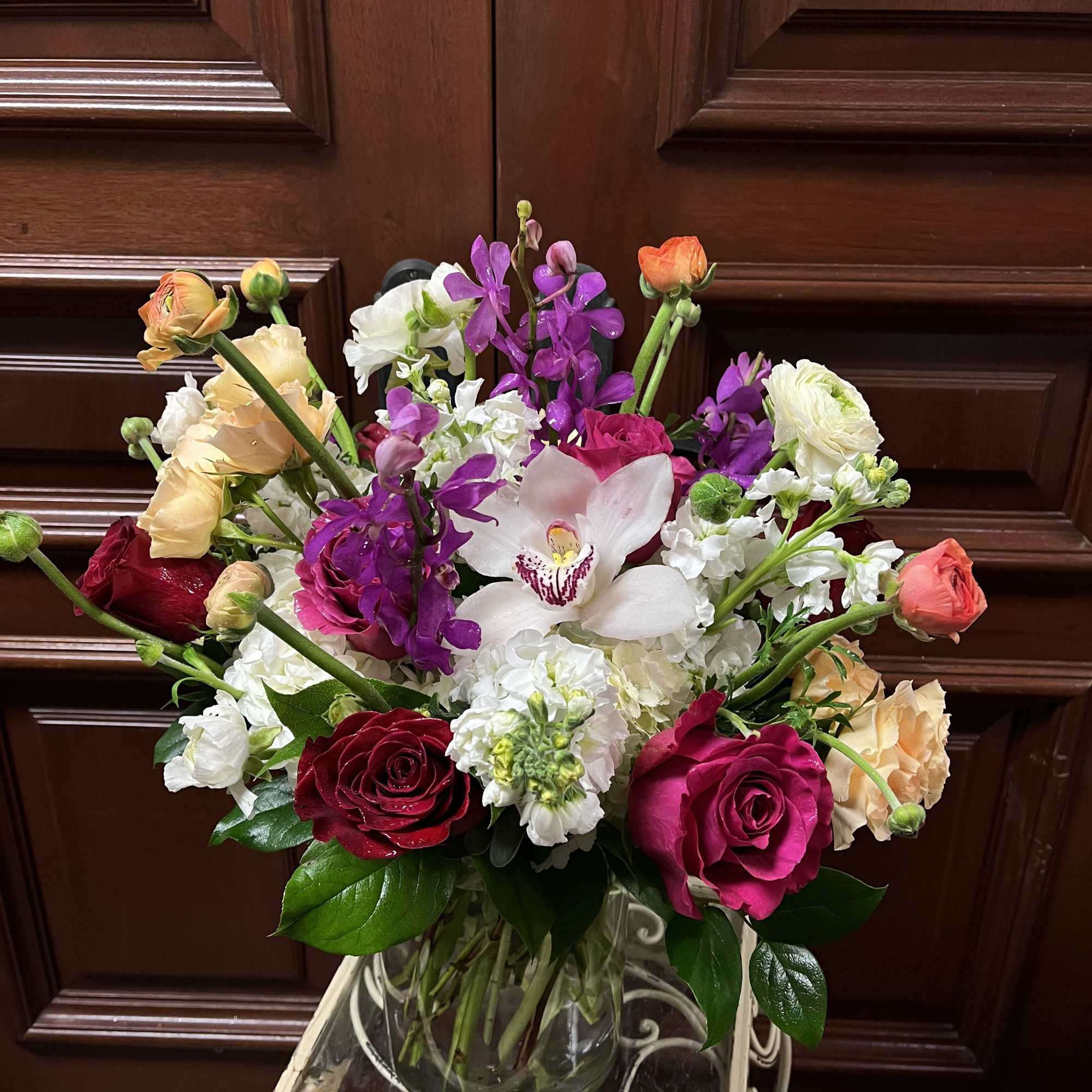 Mixed bouquet of roses, orchids, and white blooms in a glass vase, photo 2 of 2