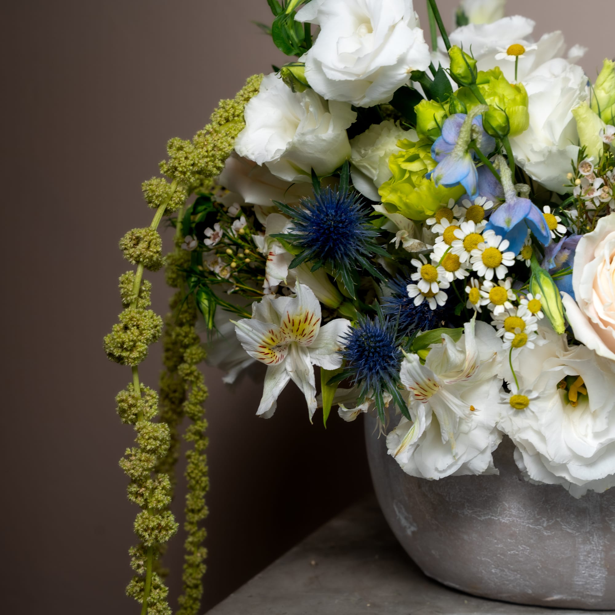 Mixed bouquet of white and blue flowers in a gray bowl vase