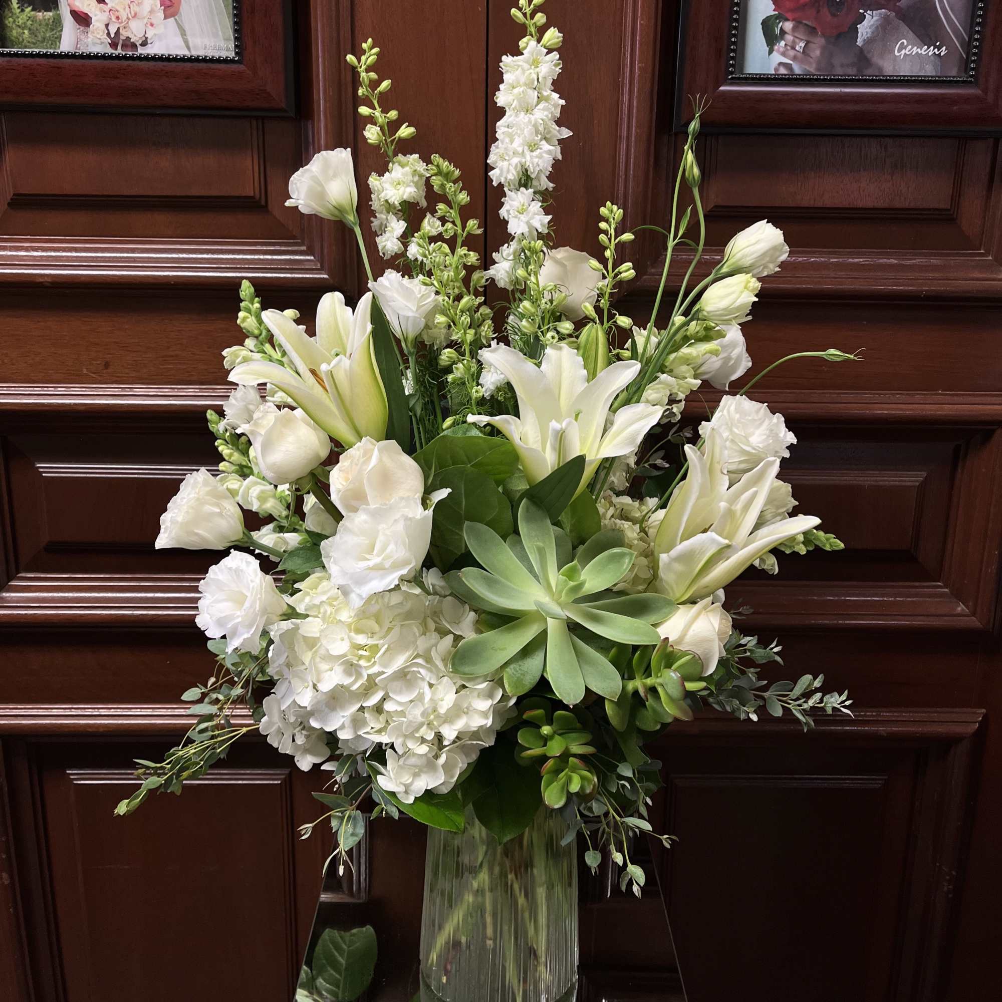 White floral arrangement in a clear glass vase with lilies and hydrangeas