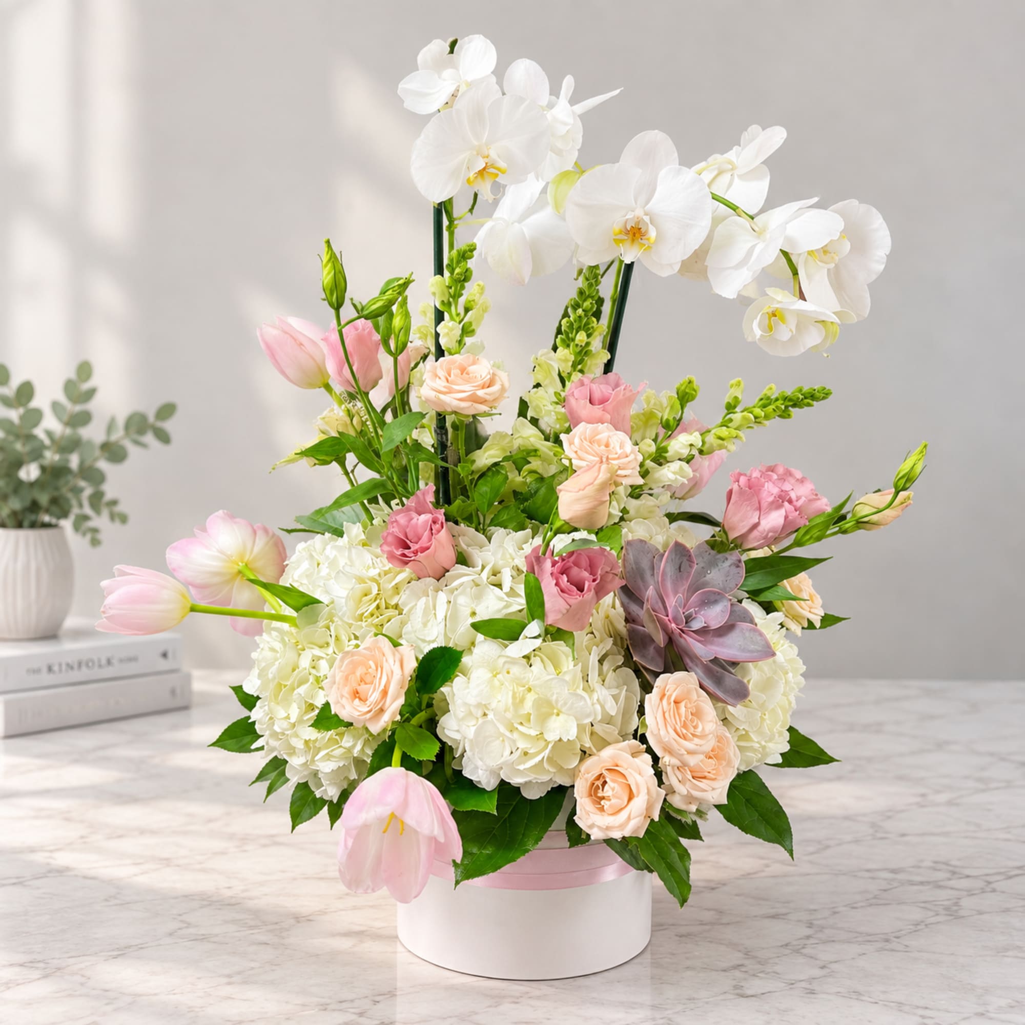 White orchids and pink roses arranged in a round white box