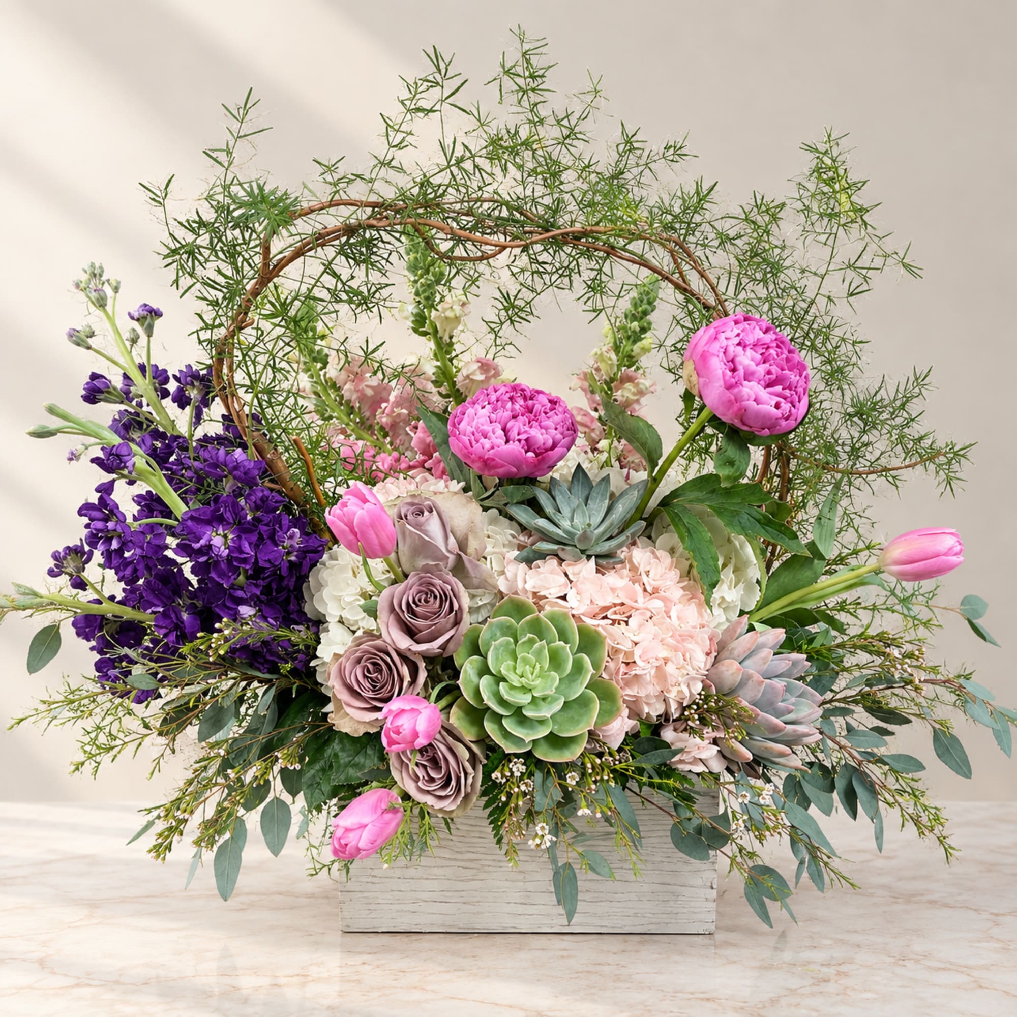 Mixed floral arrangement in a white rectangular container with pink blooms and succulents