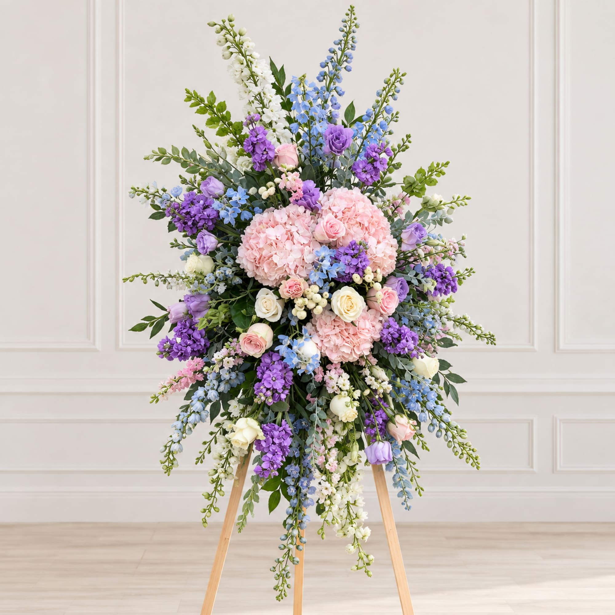 Large pastel floral standing arrangement on a wooden easel