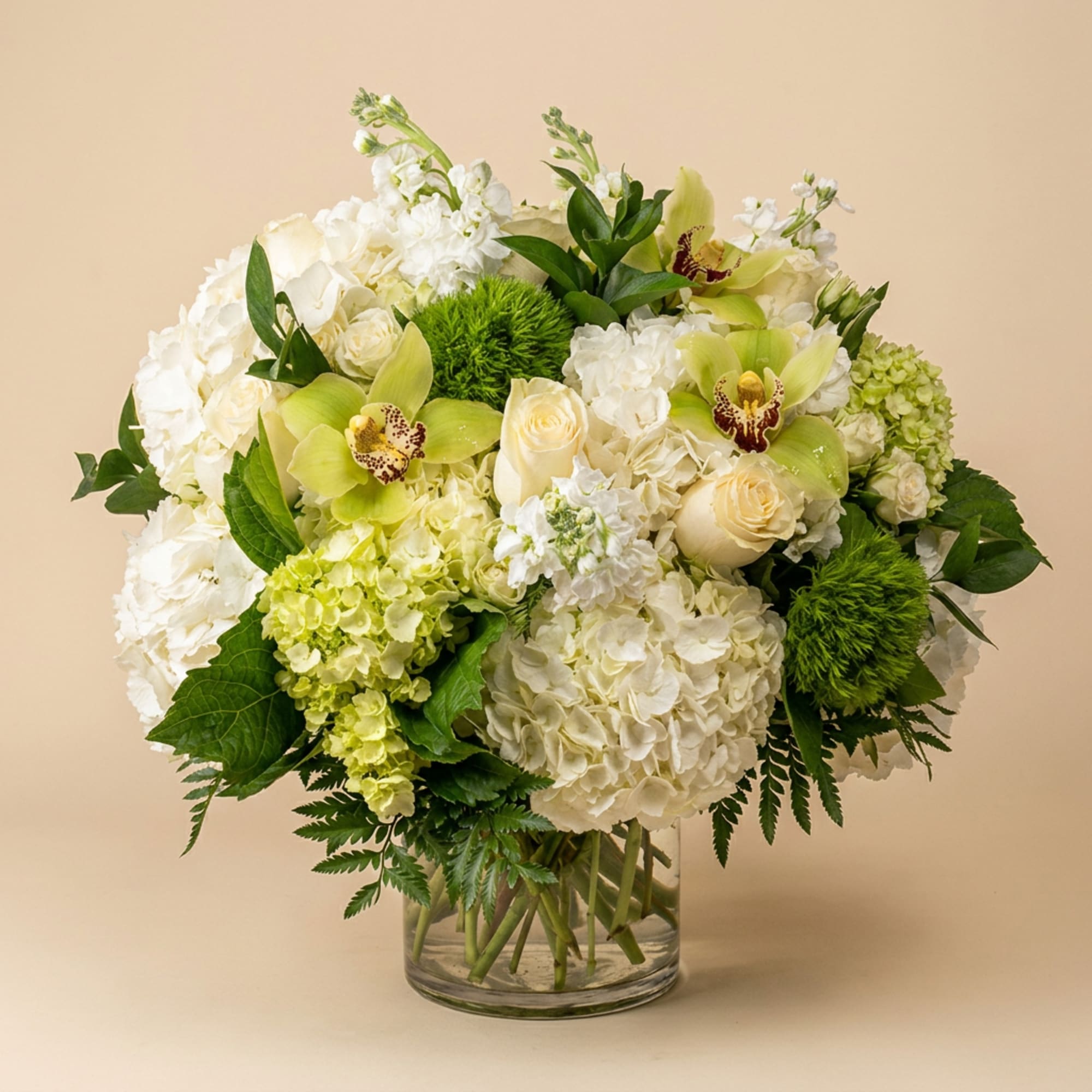 White and green bouquet with orchids and roses in a clear glass vase