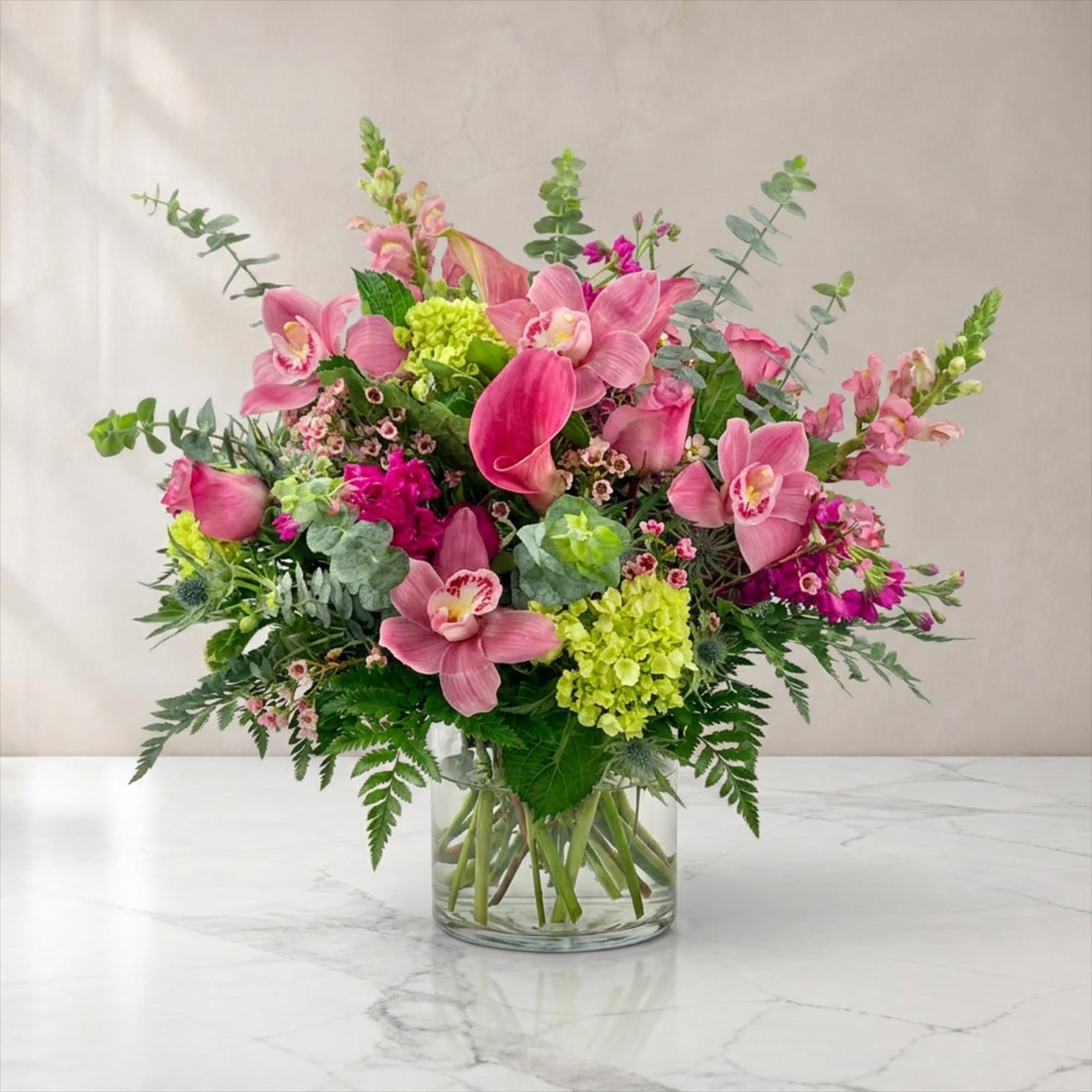 Pink orchid and calla lily arrangement in a clear glass vase