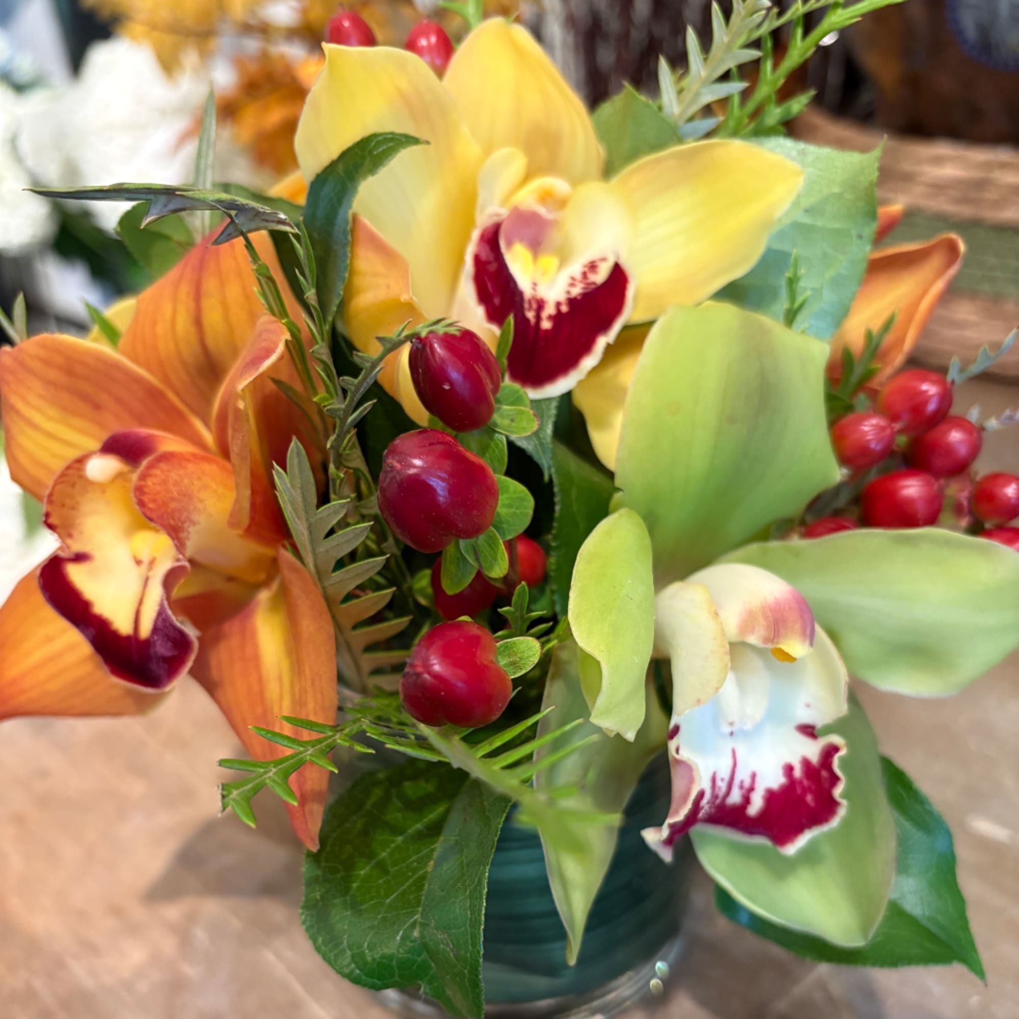 Bouquet of yellow, orange, and green orchids in a glass vase