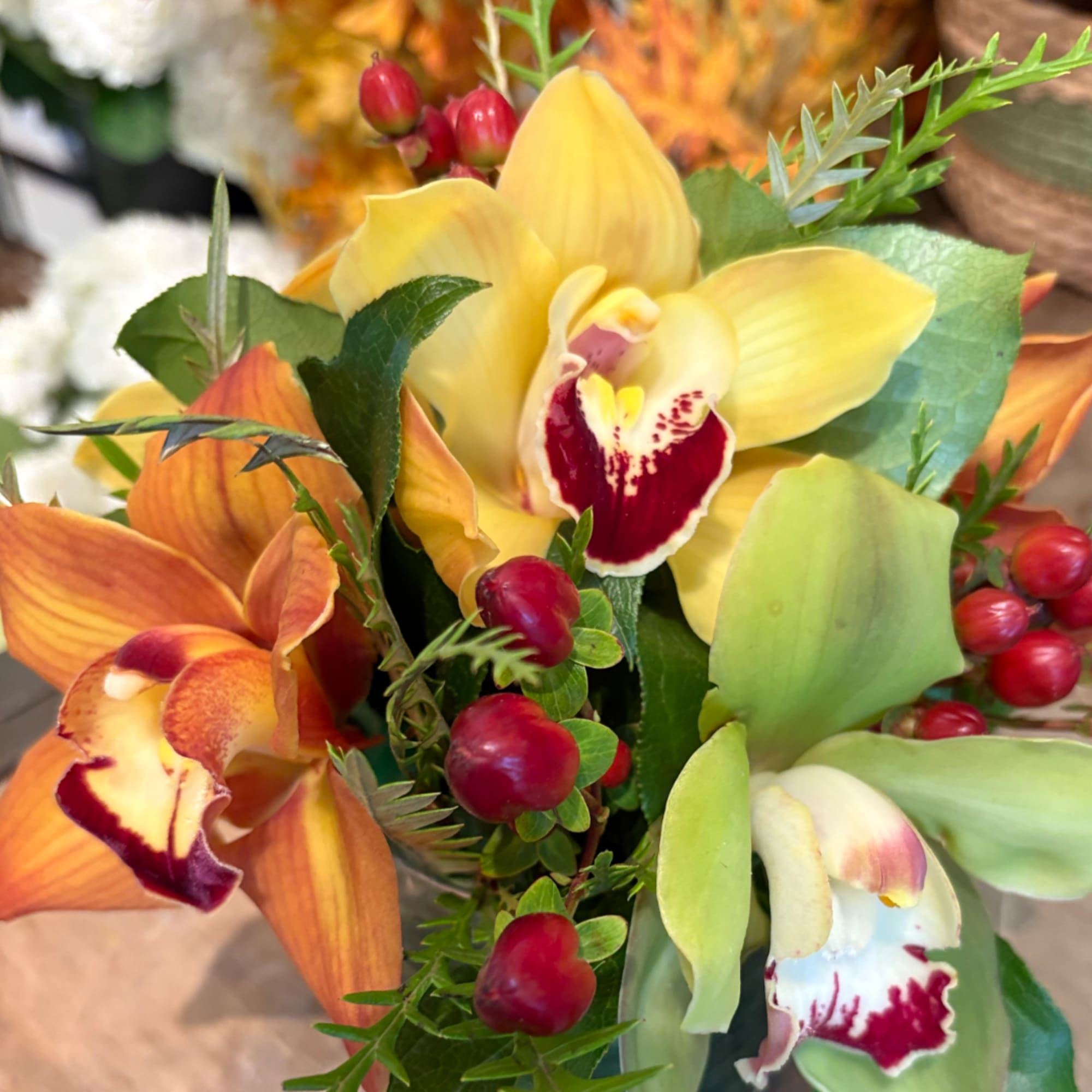 Bouquet of yellow and orange orchids with red berry accents