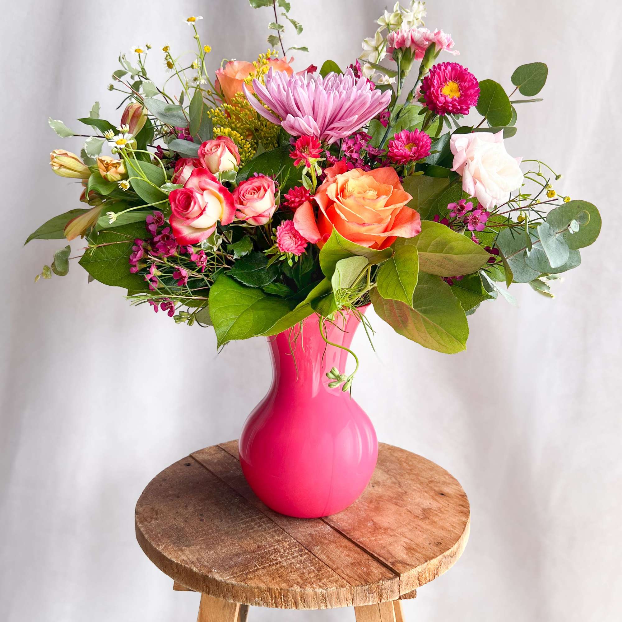 Mixed bouquet of pink, peach, and white flowers in a bright pink vase