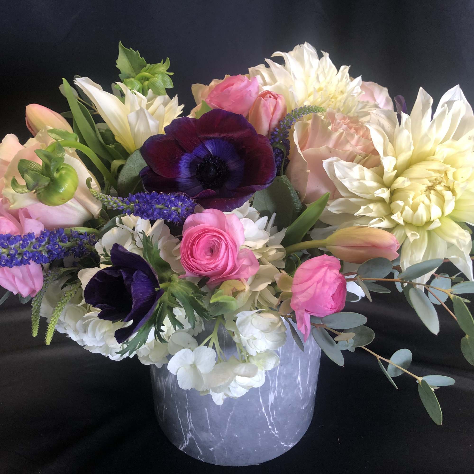 Mixed bouquet of pink, white, and purple flowers in a gray vase