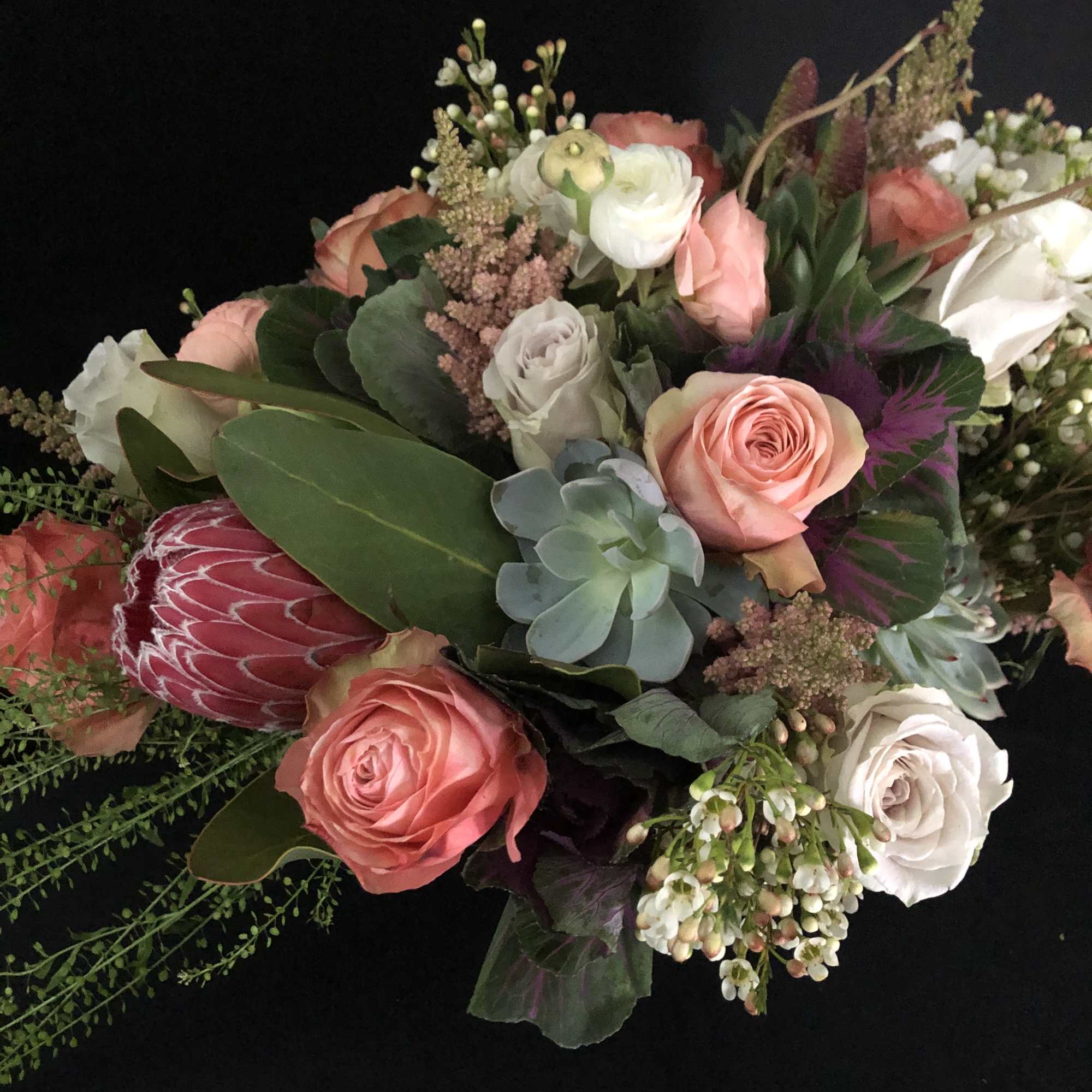 Arrangement of peach and cream roses with protea and succulents in a lush mixed bouquet